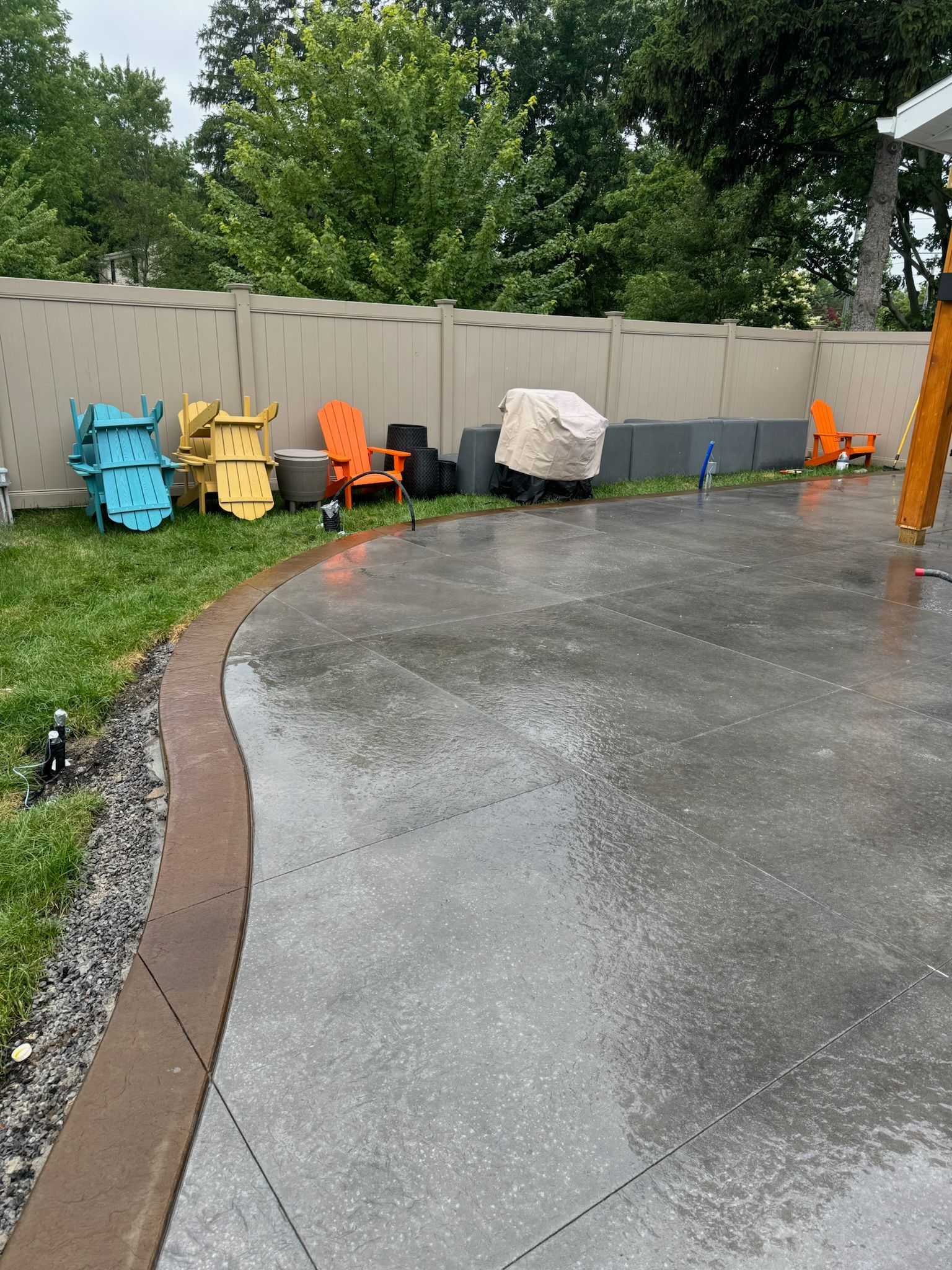 A row of colorful chairs are lined up on a concrete driveway.