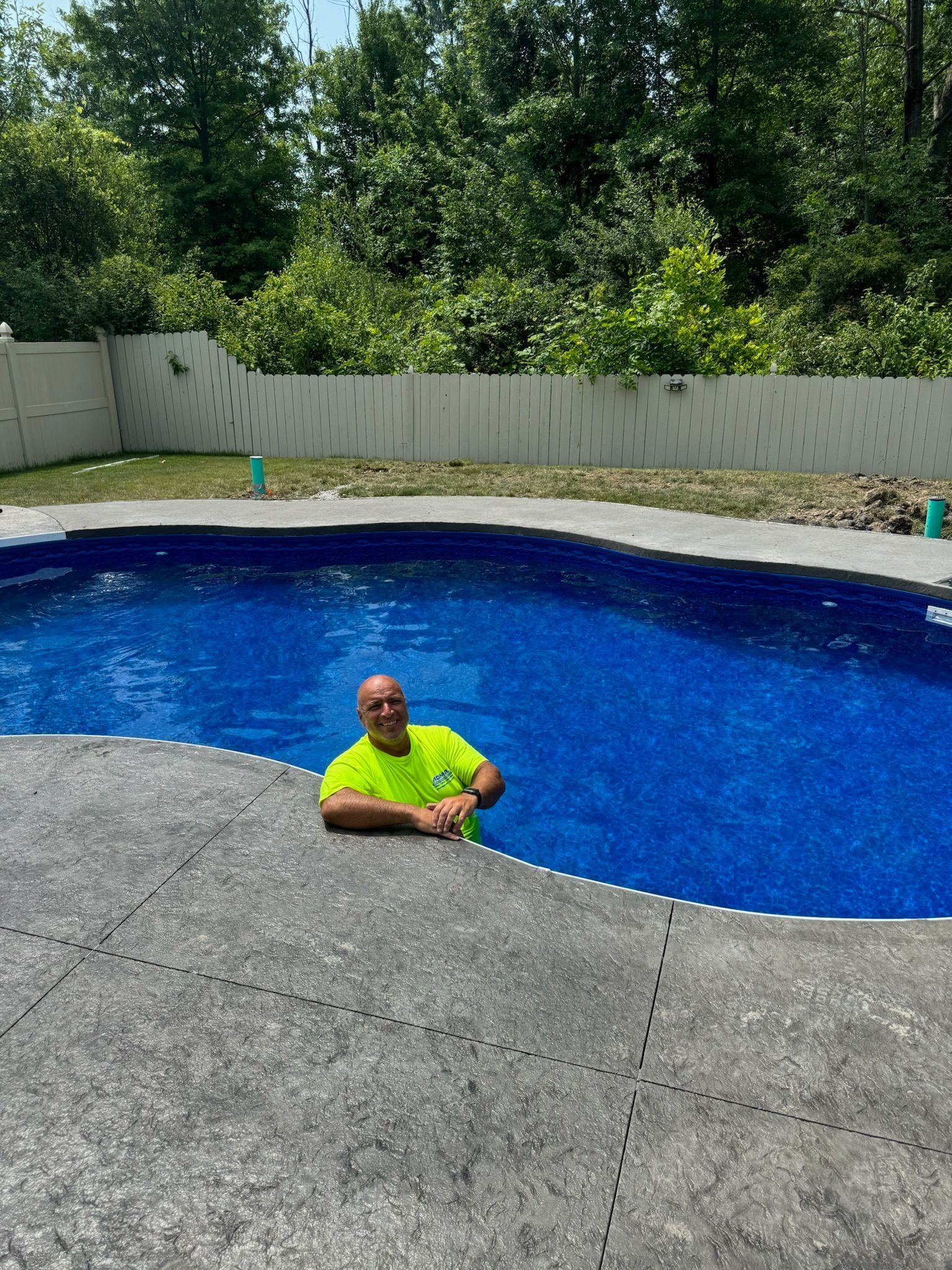 A man in a neon yellow shirt is standing in a swimming pool.