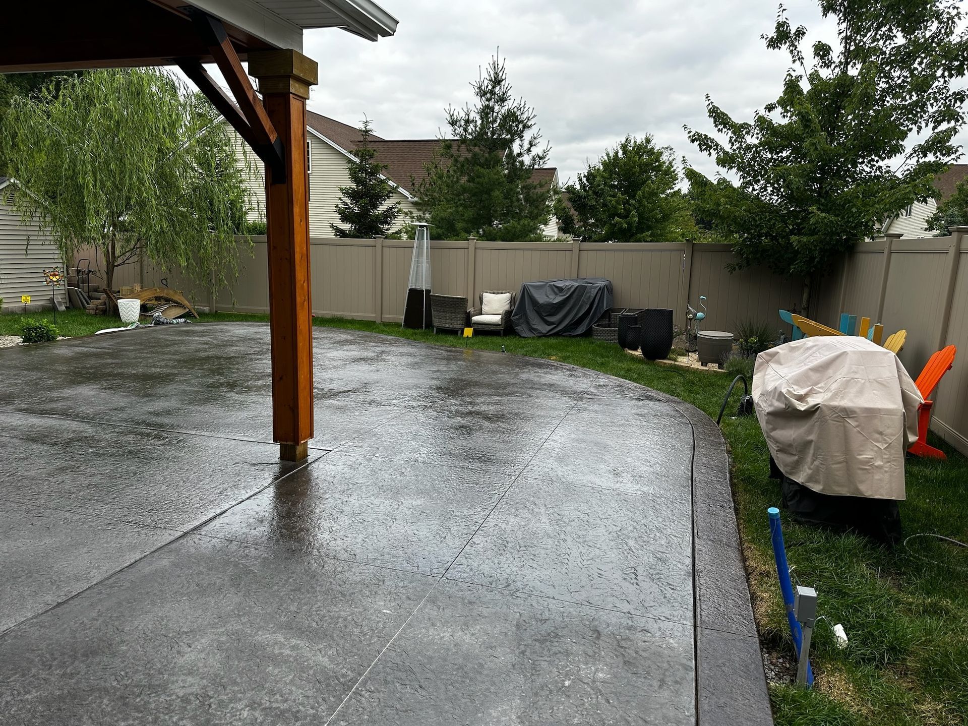 A backyard with a concrete driveway and a wooden fence.