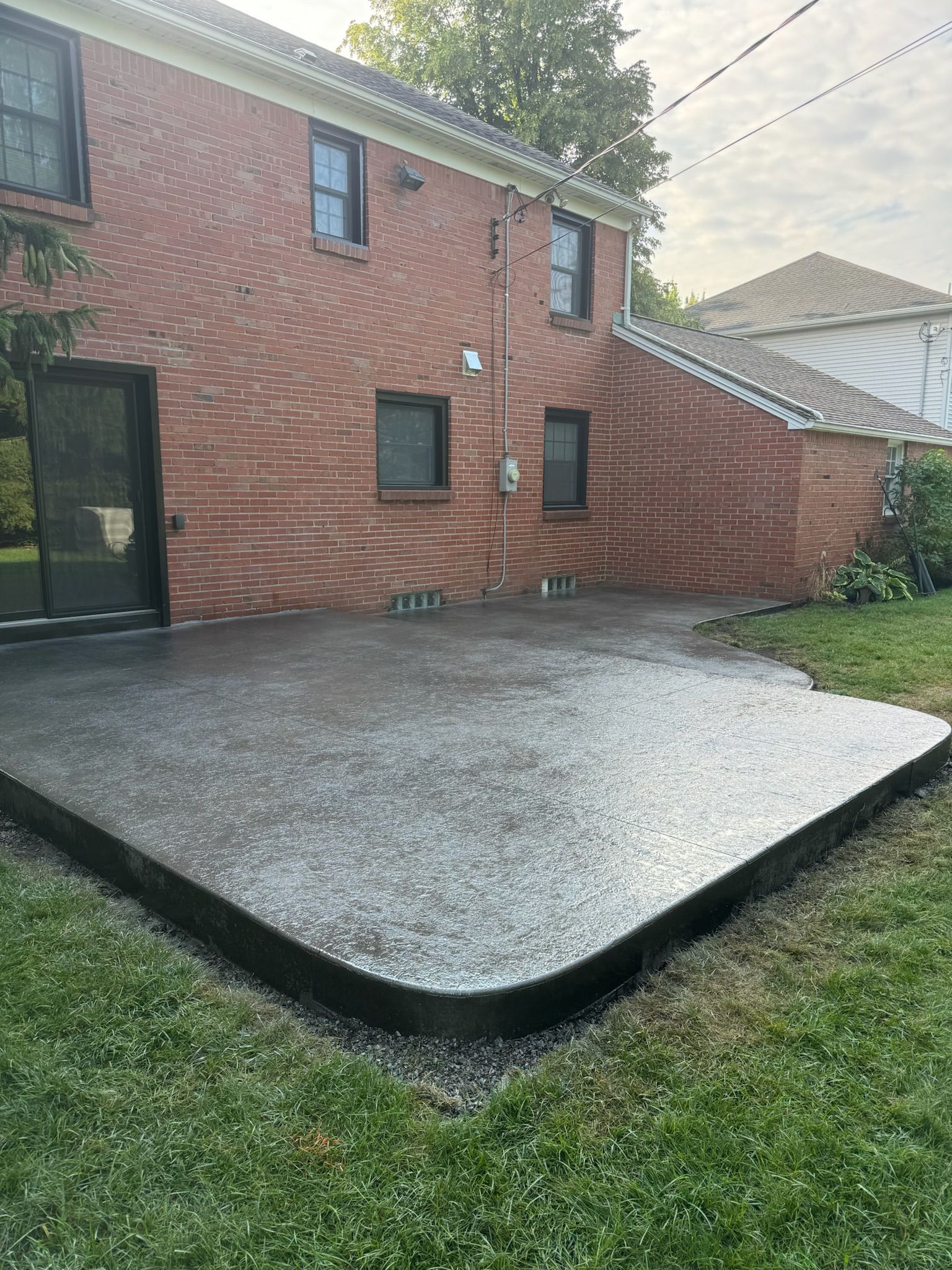 A brick house with a concrete patio in front of it.