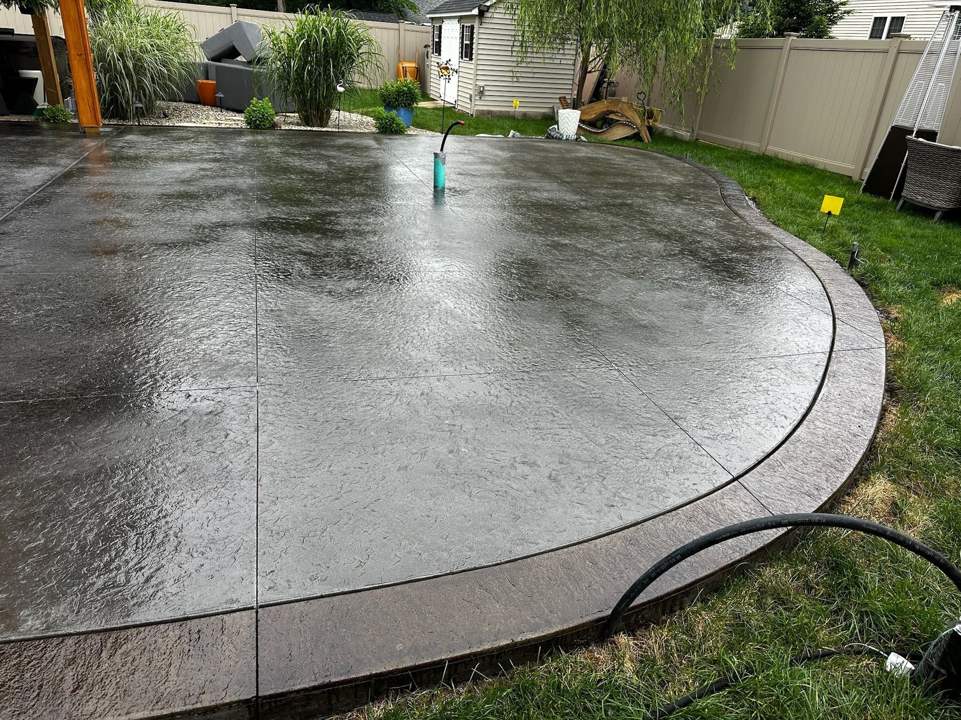 A concrete patio with a hose attached to it in a backyard.