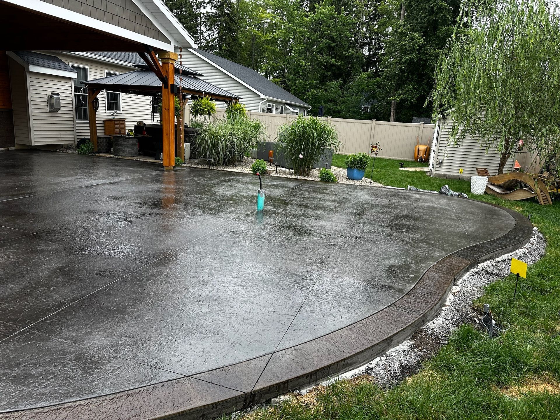A concrete driveway in a backyard with a house in the background.