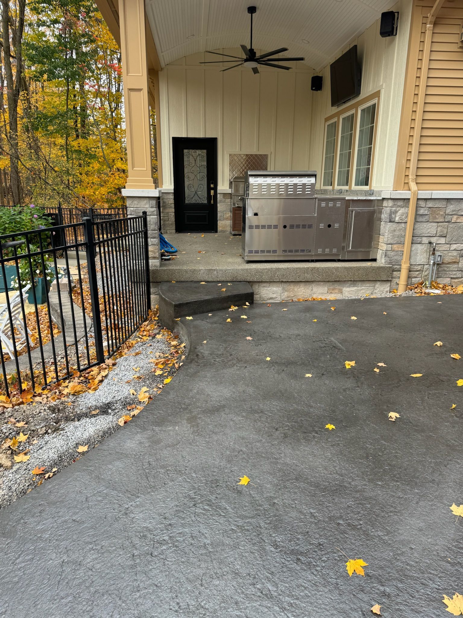A porch with a grill and a ceiling fan