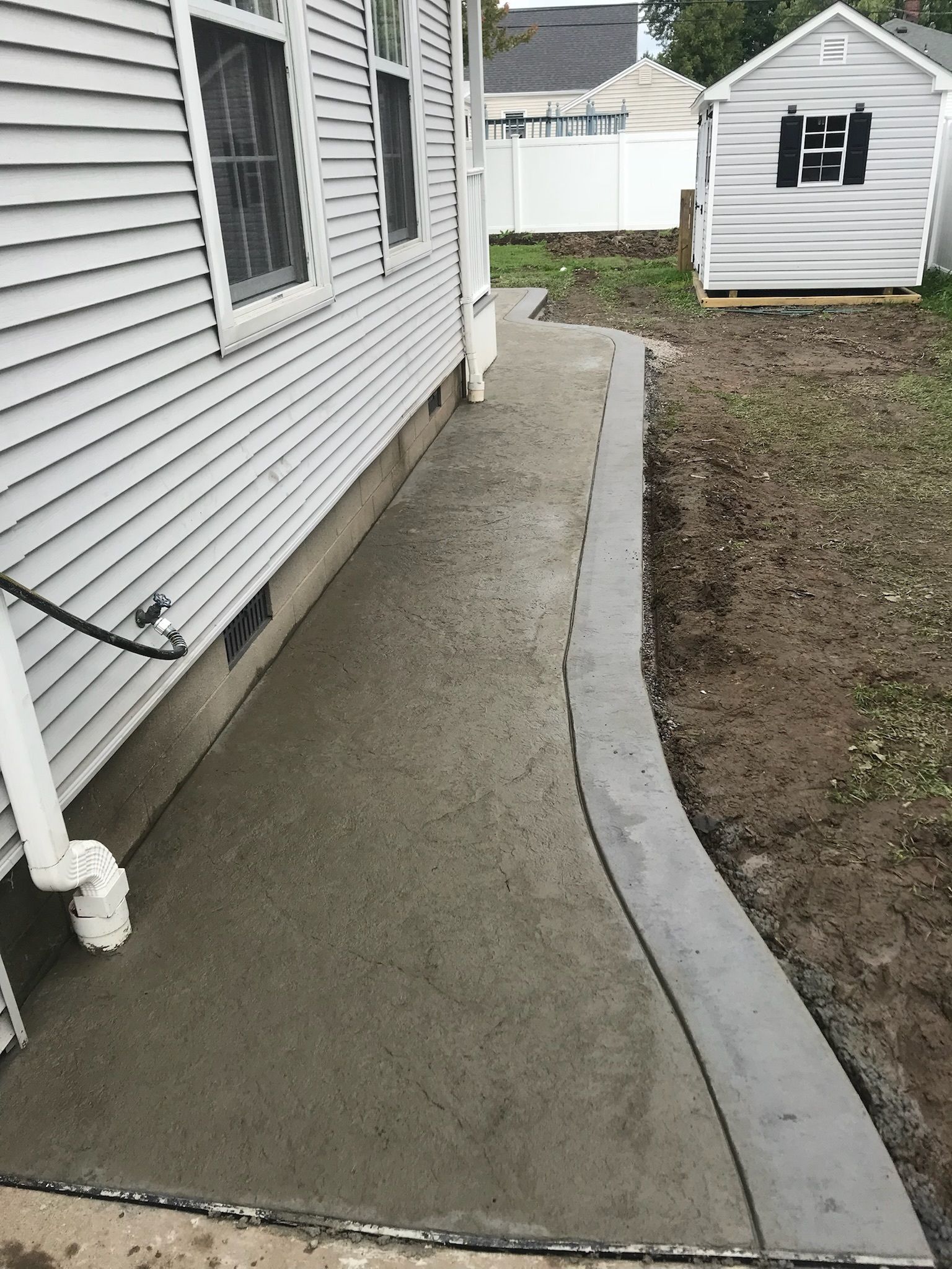 A concrete walkway is being built in front of a house.