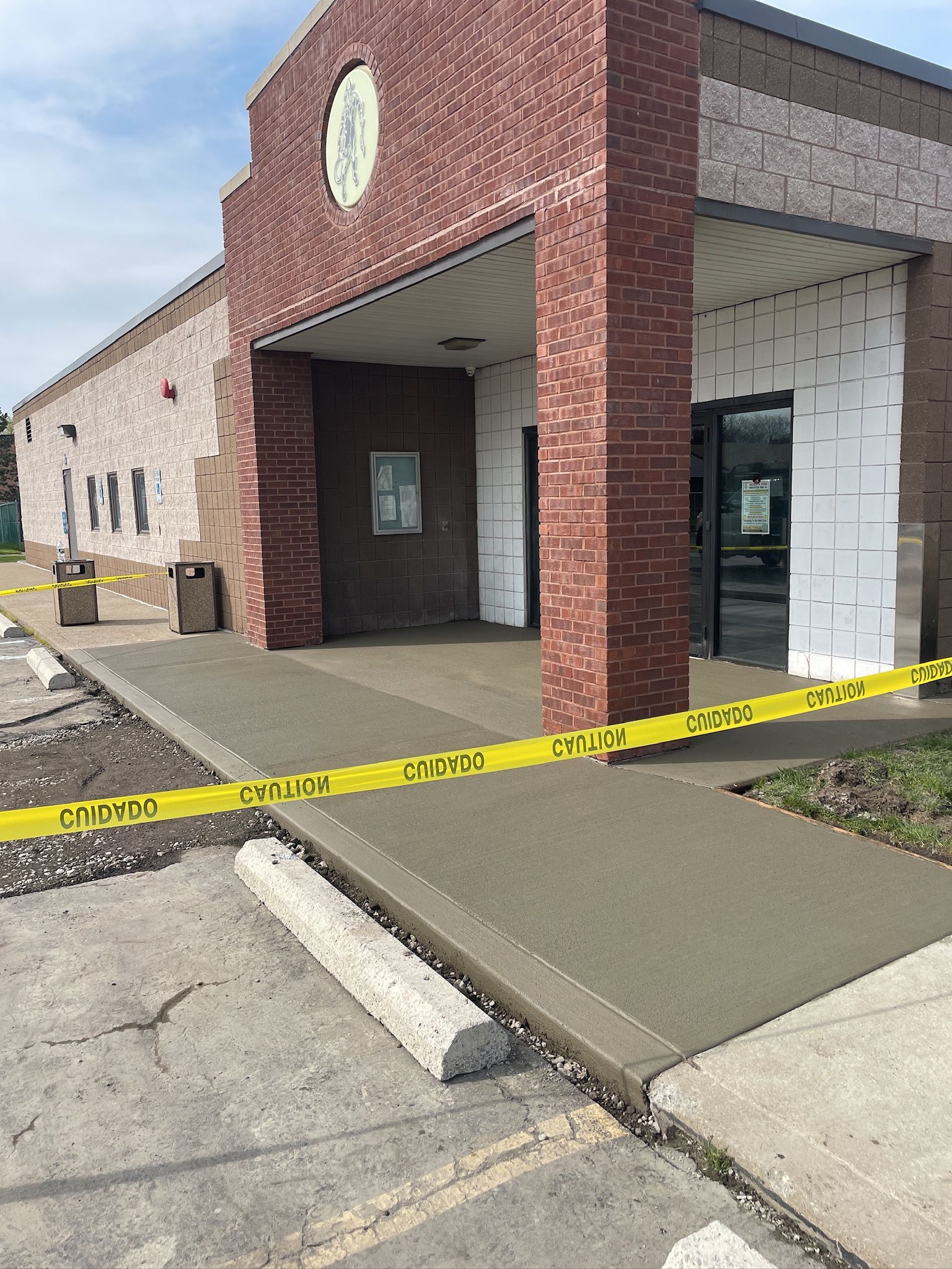 A brick building with a yellow tape covering the sidewalk in front of it.