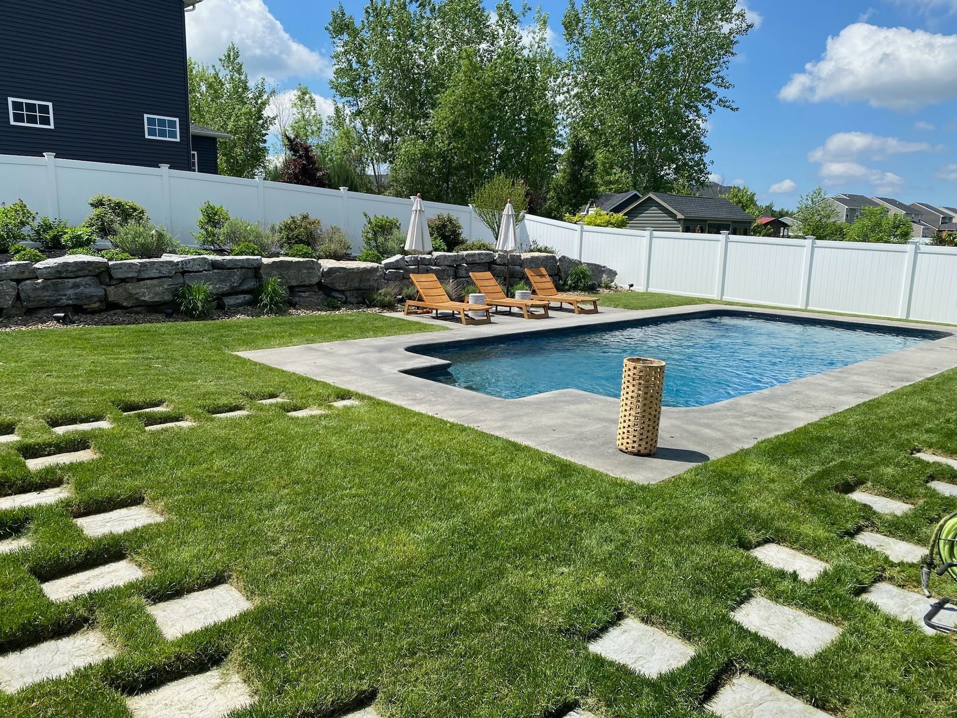 There is a large swimming pool in the backyard of a house.
