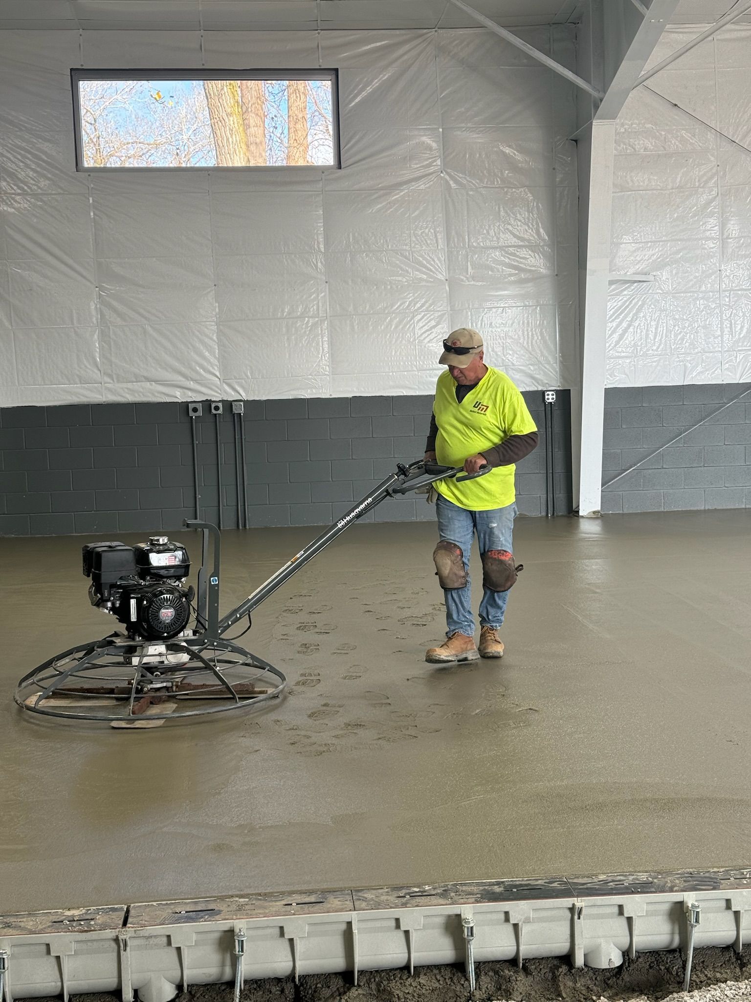 A man is using a machine to level a concrete floor.