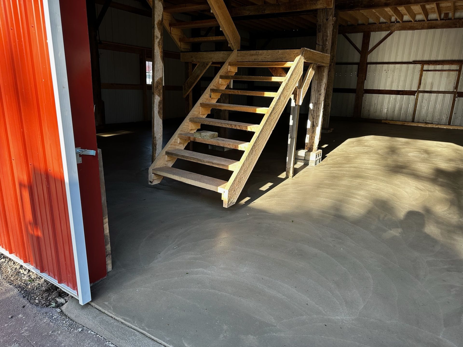 A wooden staircase in a garage next to a red door