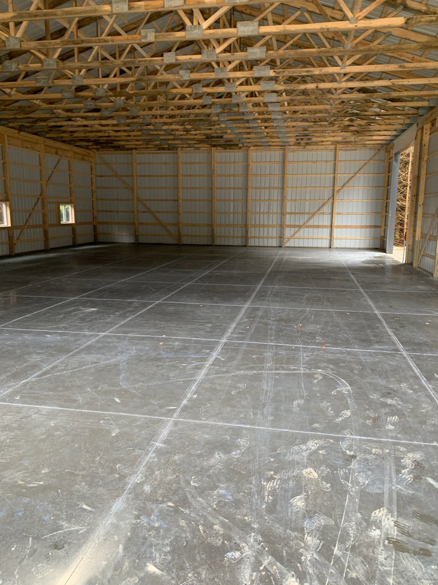 A large empty building with a concrete floor and wooden beams.
