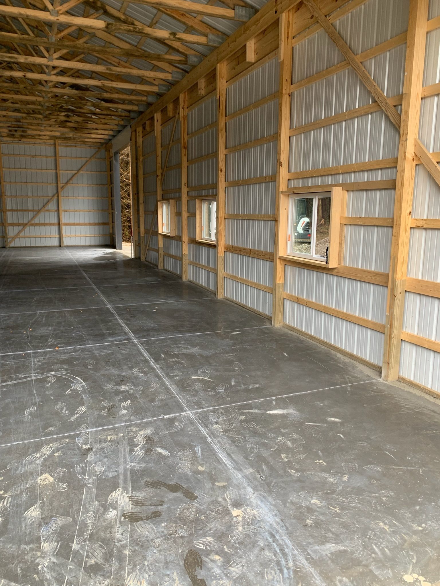 A large empty building with wooden beams and a concrete floor.