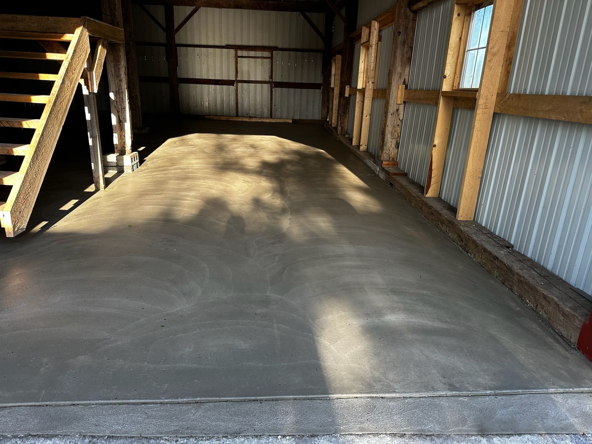 A concrete floor in a barn with stairs leading up to it.