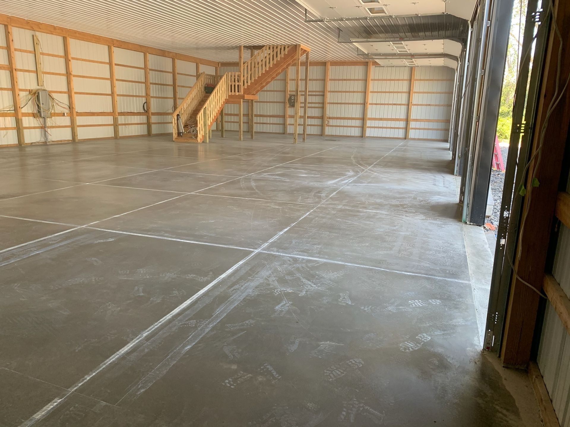 A large empty building with a staircase and a concrete floor.