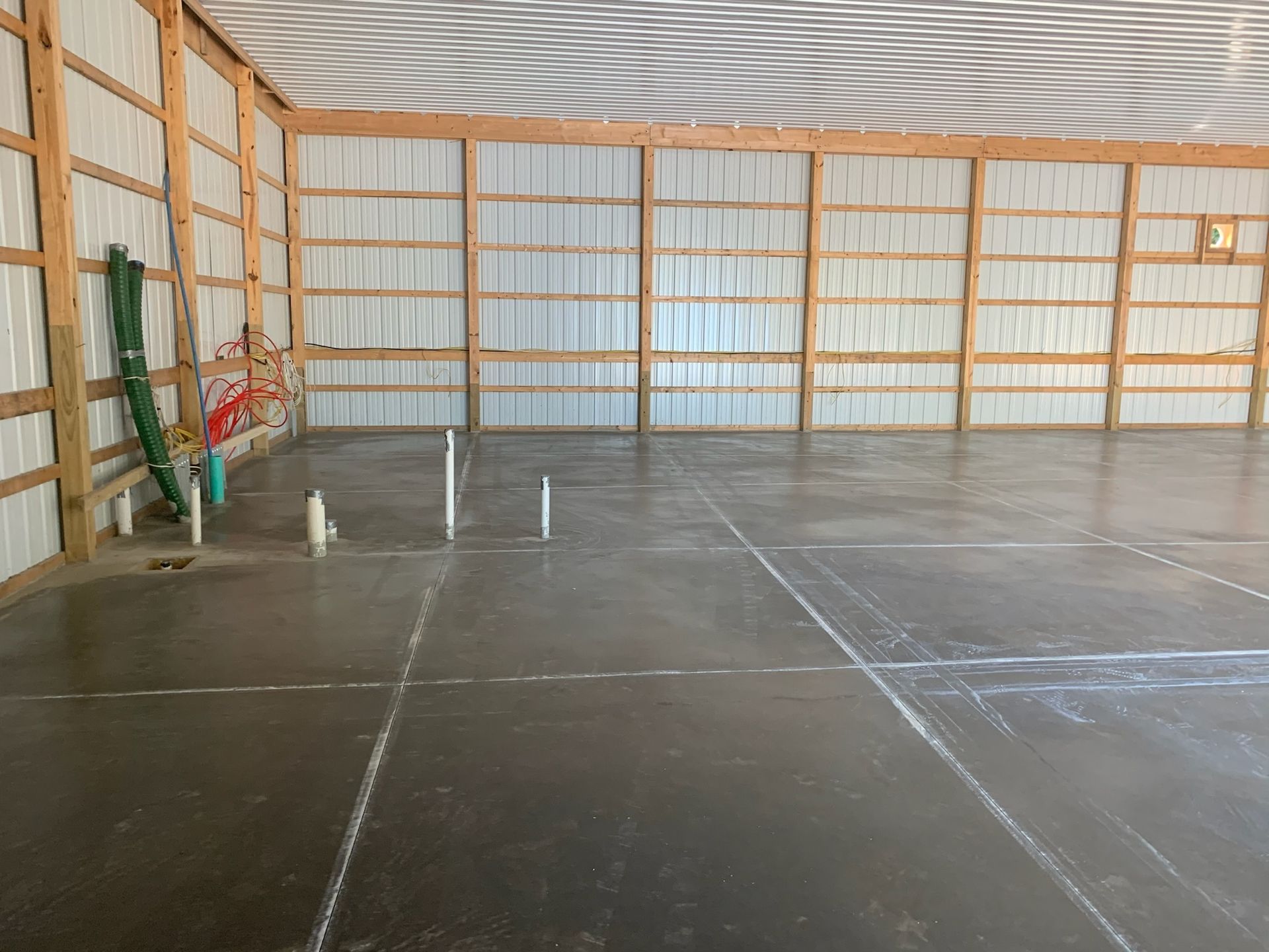 A large empty building with a concrete floor and wooden walls.
