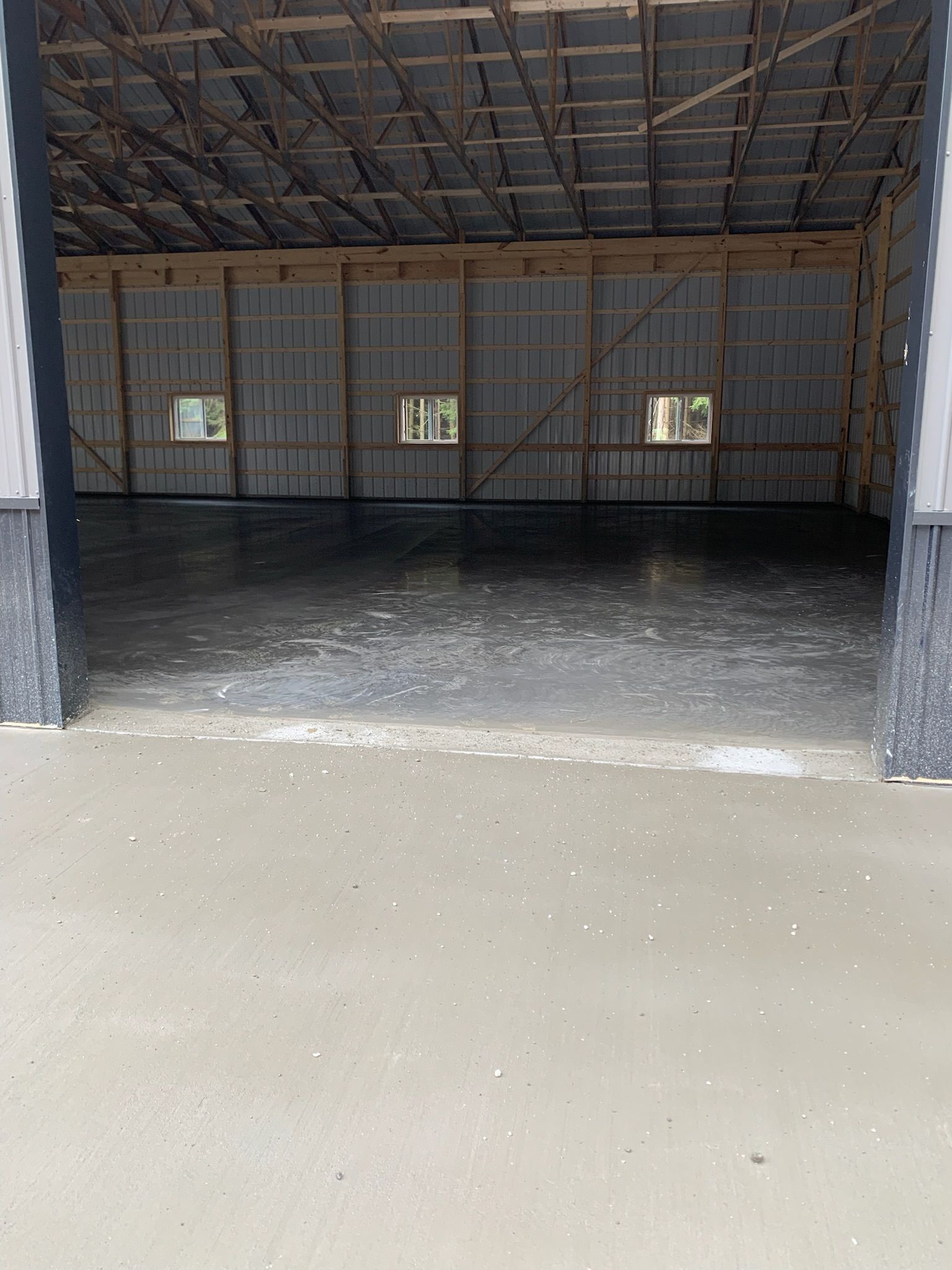 A large empty building with a concrete floor and a wooden roof.