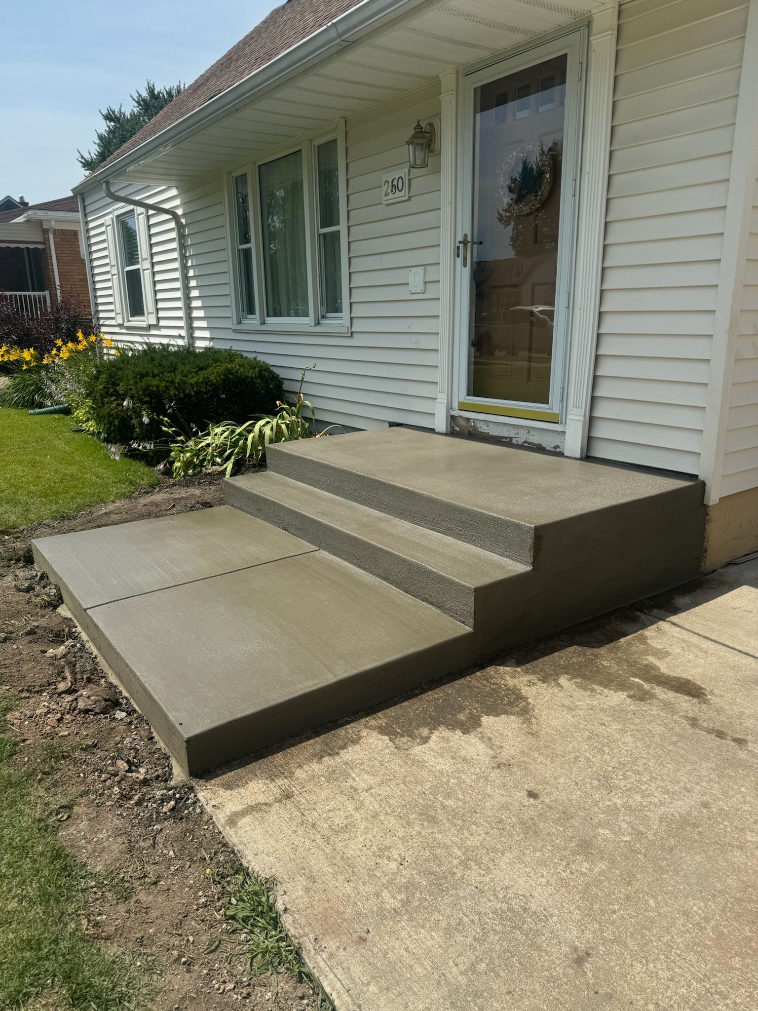 A white house with concrete steps leading up to the front door.