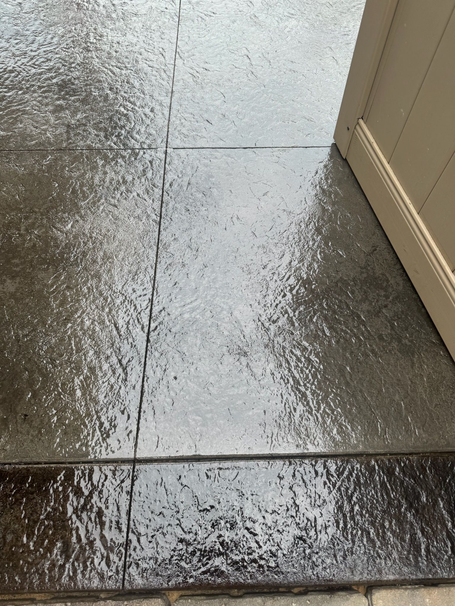 A close up of a wet tile floor next to a door.