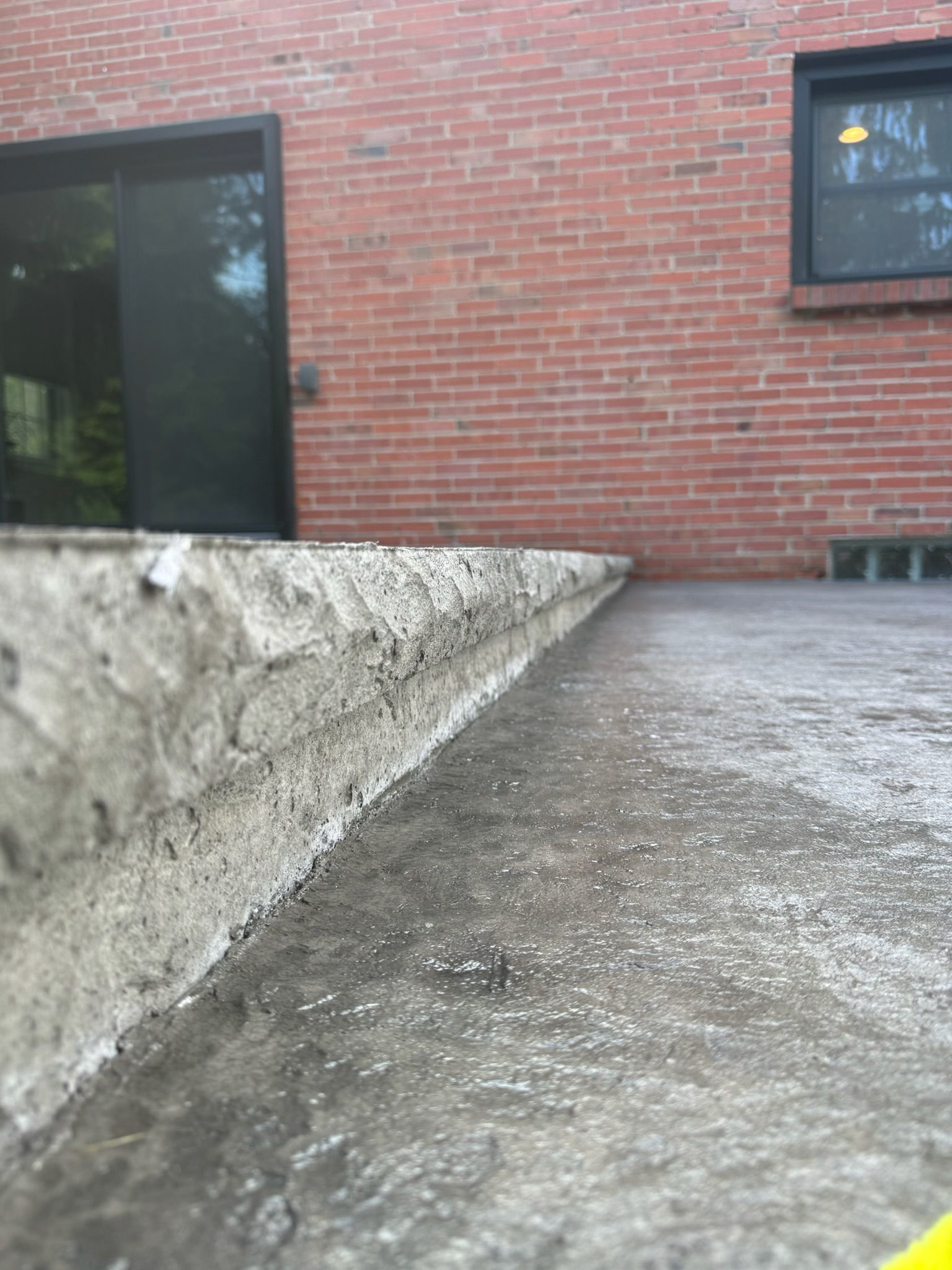A brick building with a concrete walkway in front of it.