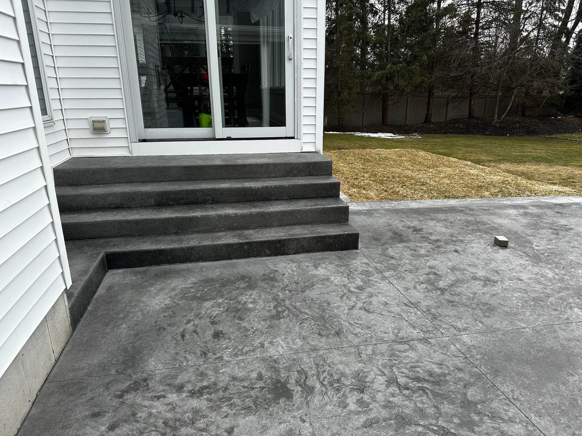 A concrete patio with stairs leading up to a house.