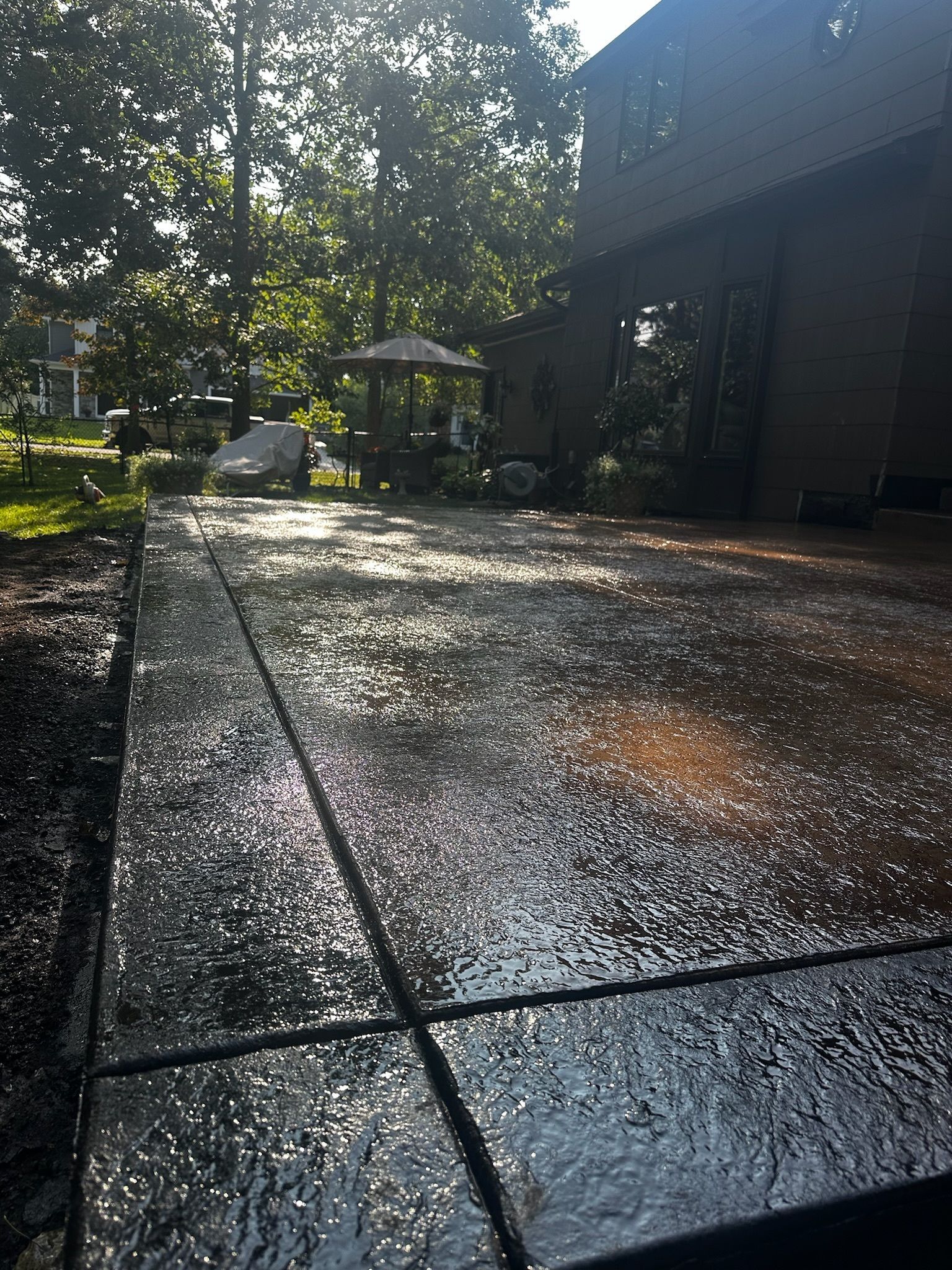A concrete driveway leading to a house with trees in the background.