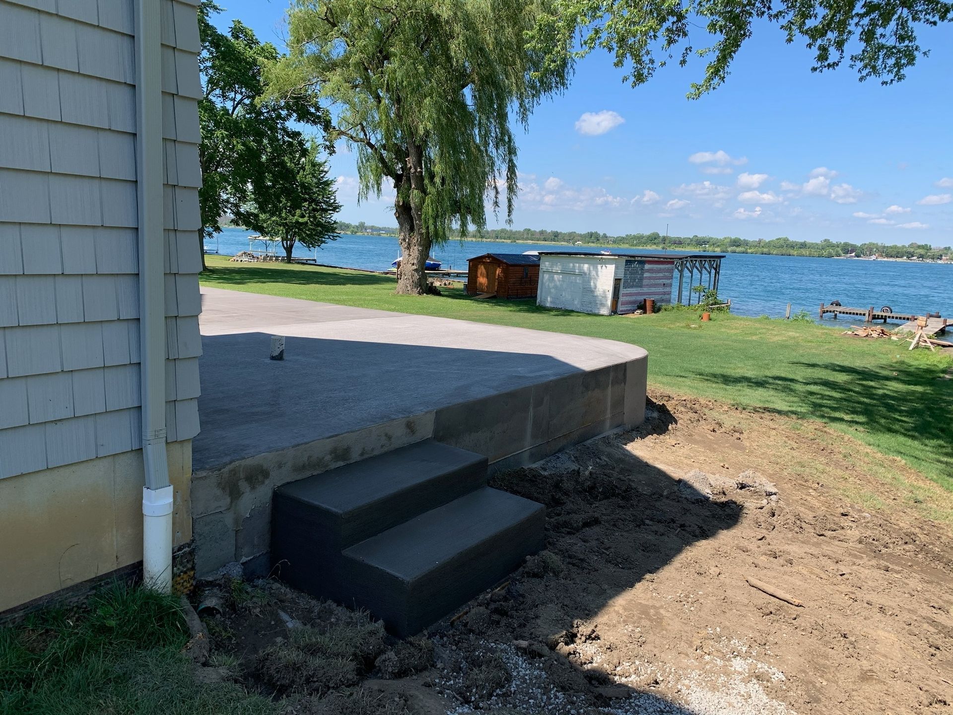 A concrete staircase is being built next to a house next to a body of water.