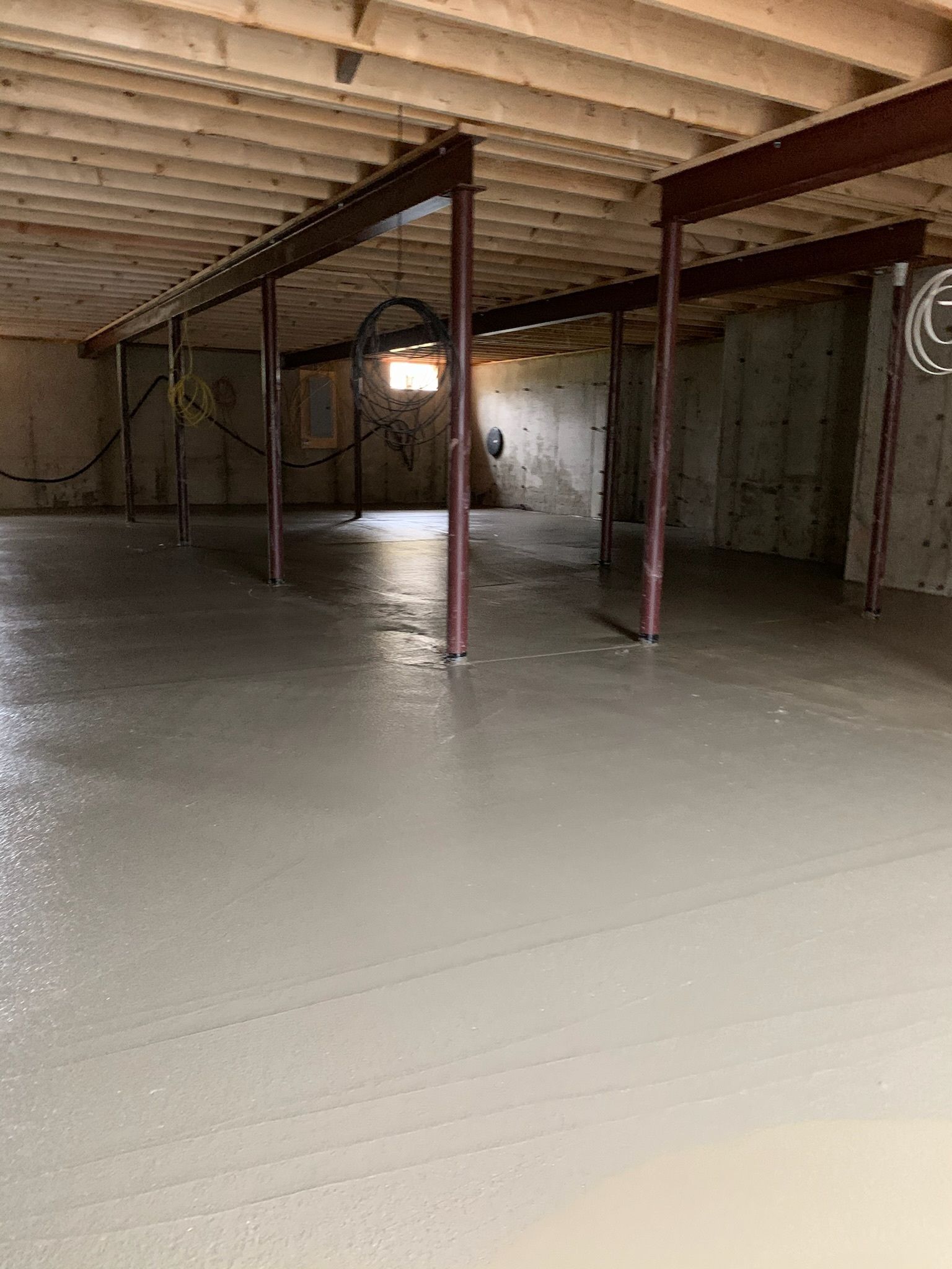 An empty basement with a concrete floor and a ceiling.