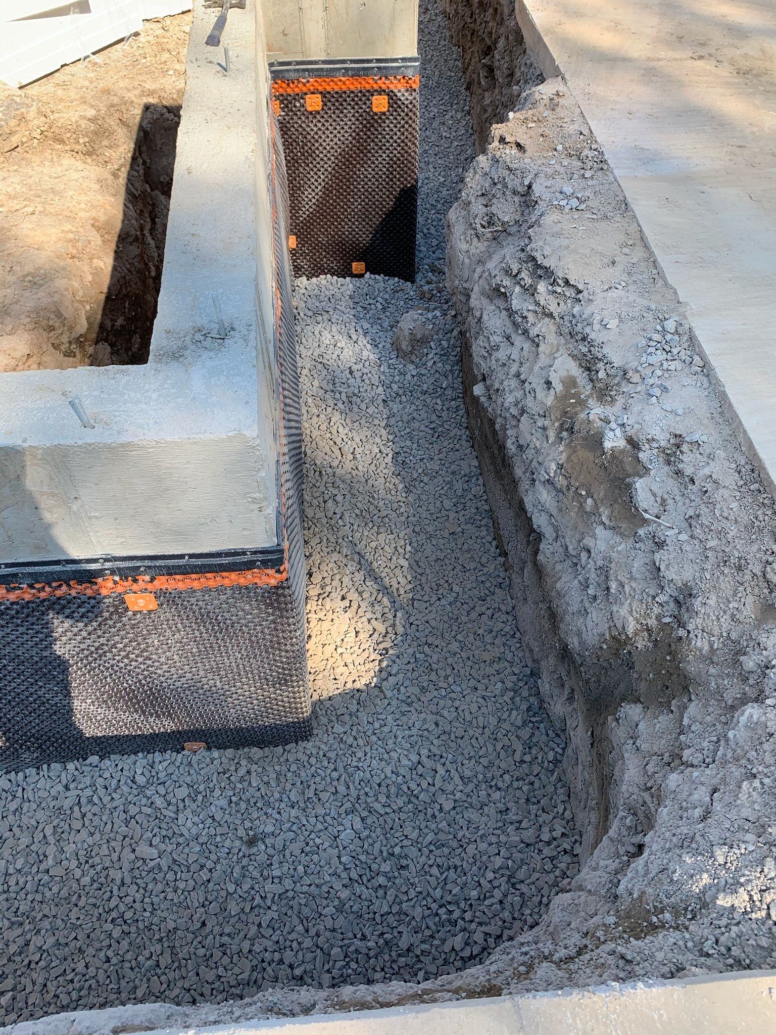 A pile of gravel is being poured into a hole in the ground.