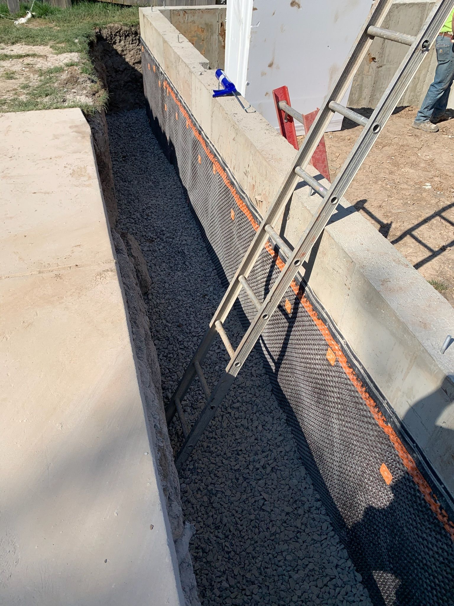 A ladder is sitting on top of a concrete wall.
