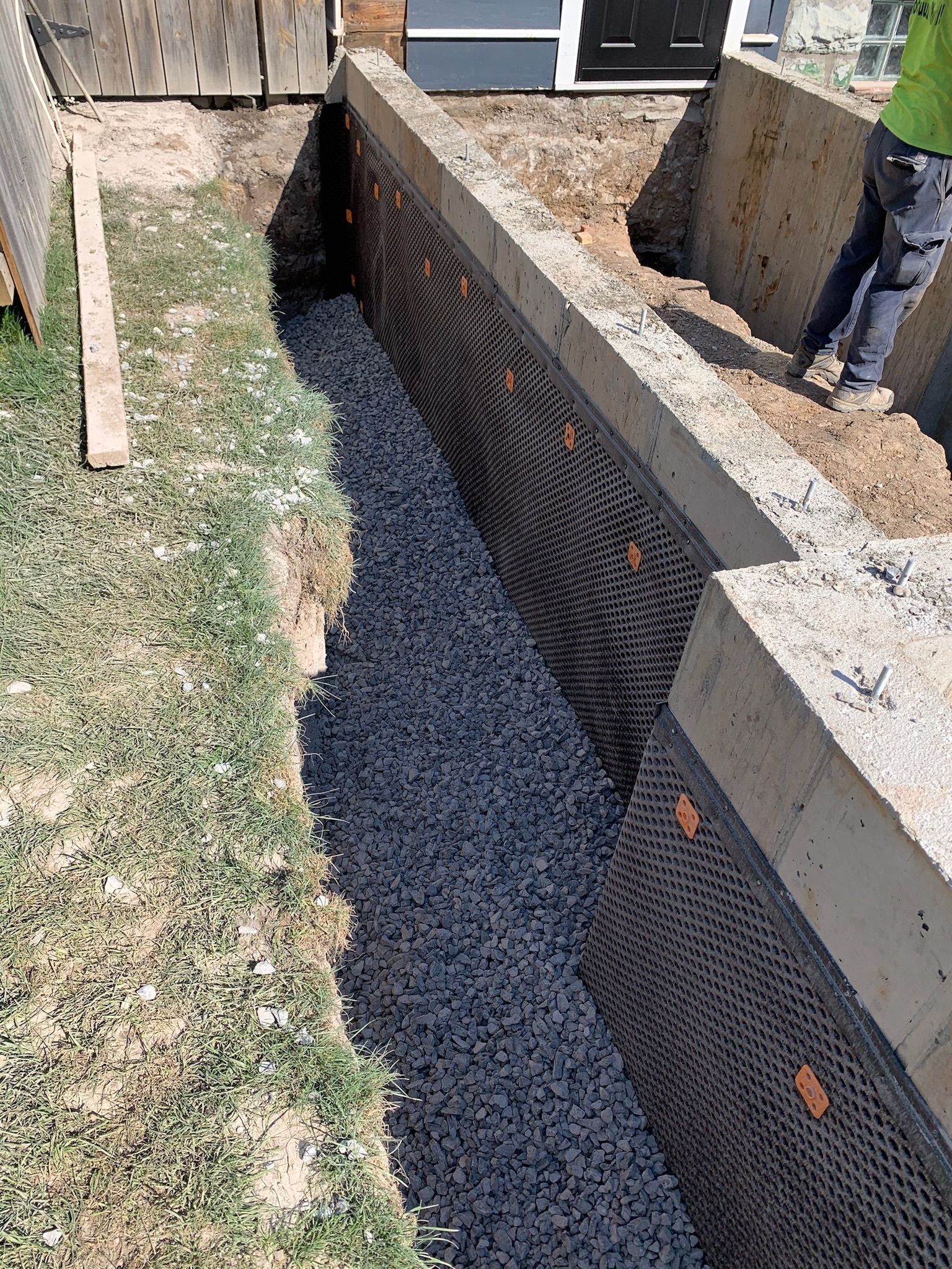 A man is working on a drainage system in a backyard.