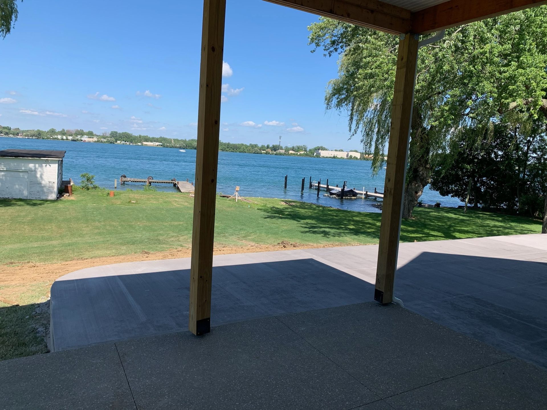 A view of a lake from a porch with a dock in the background.