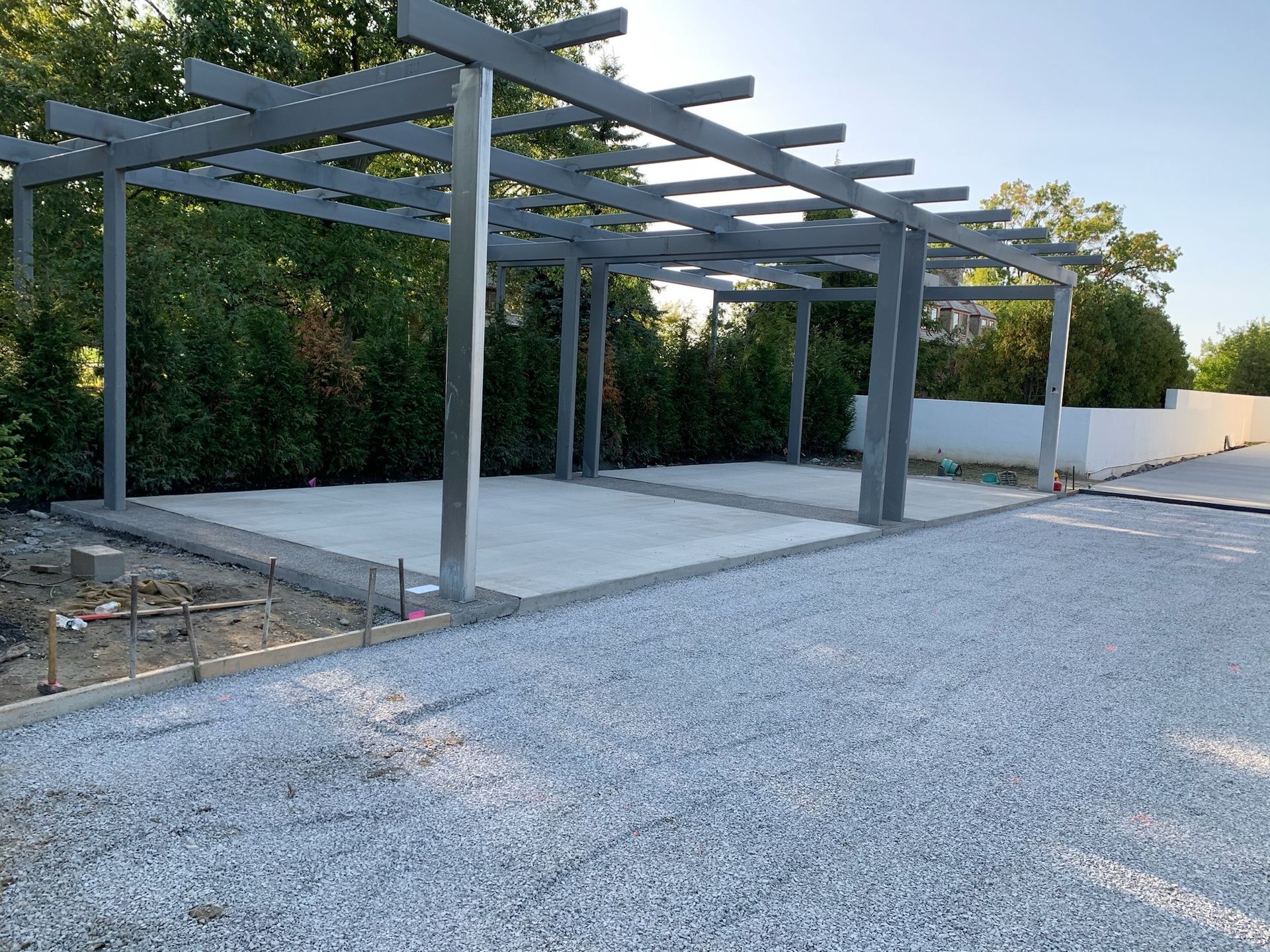 A carport is being built in the middle of a gravel driveway.