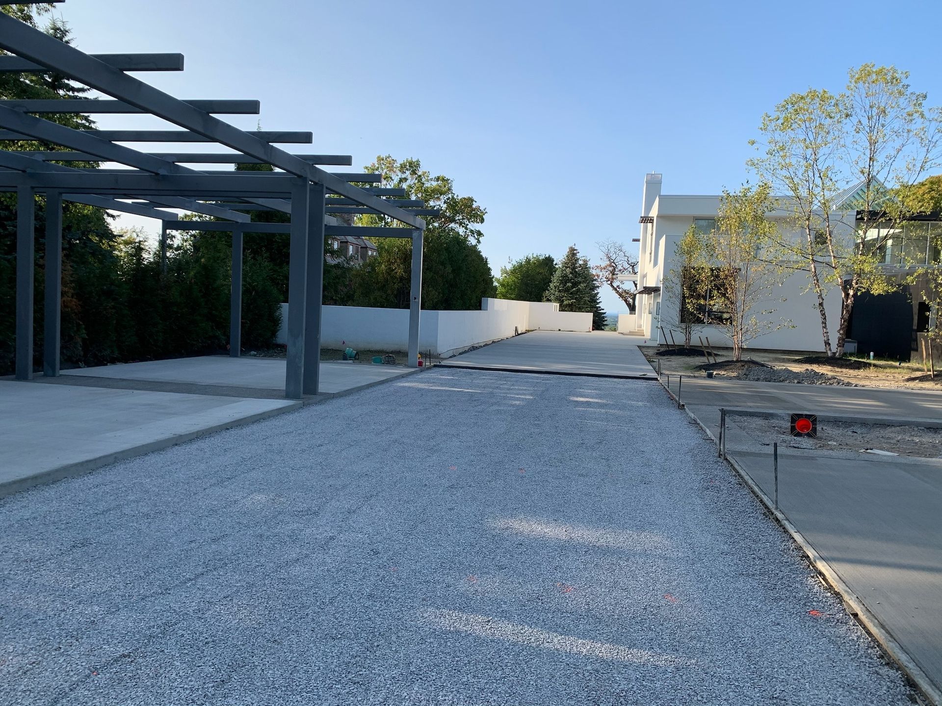 A gravel driveway leading to a house with a pergola.