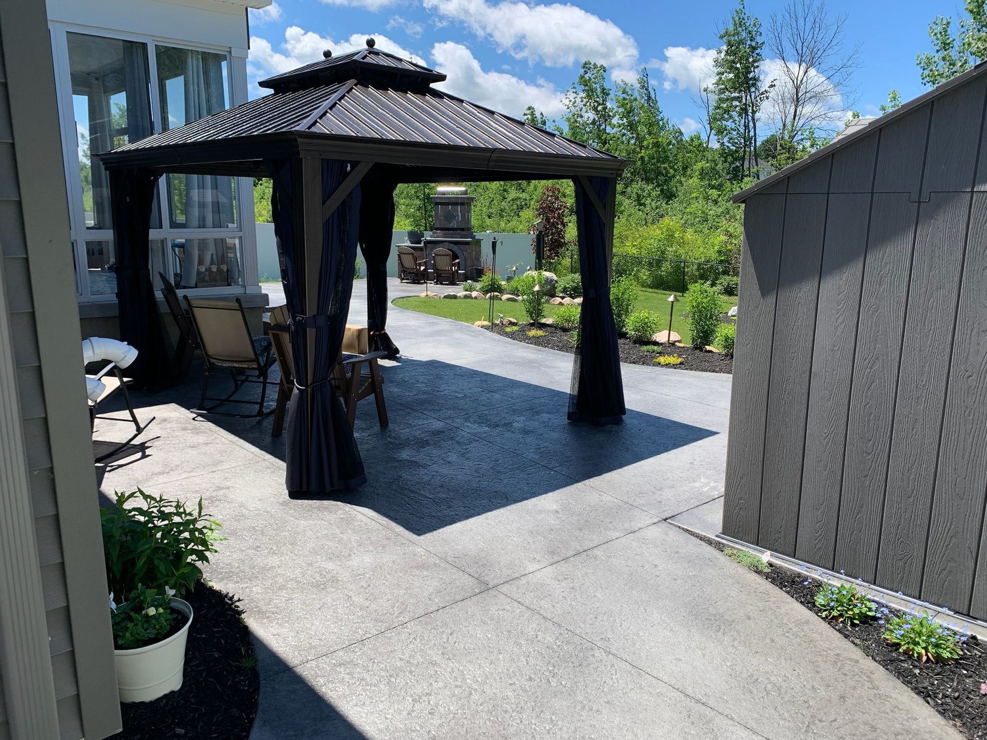 A gazebo is sitting on a patio next to a house.