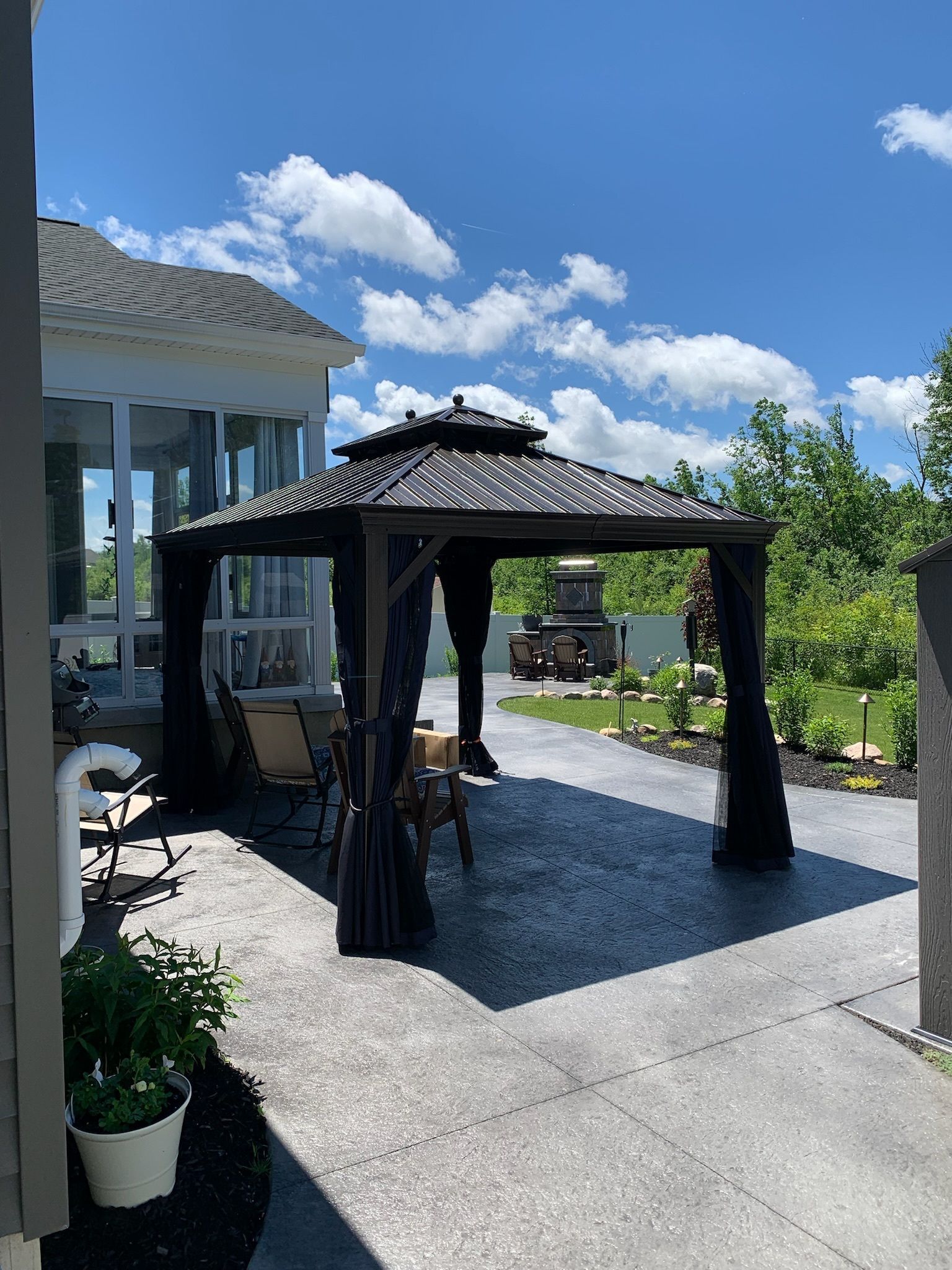 A gazebo is sitting on a patio next to a house.