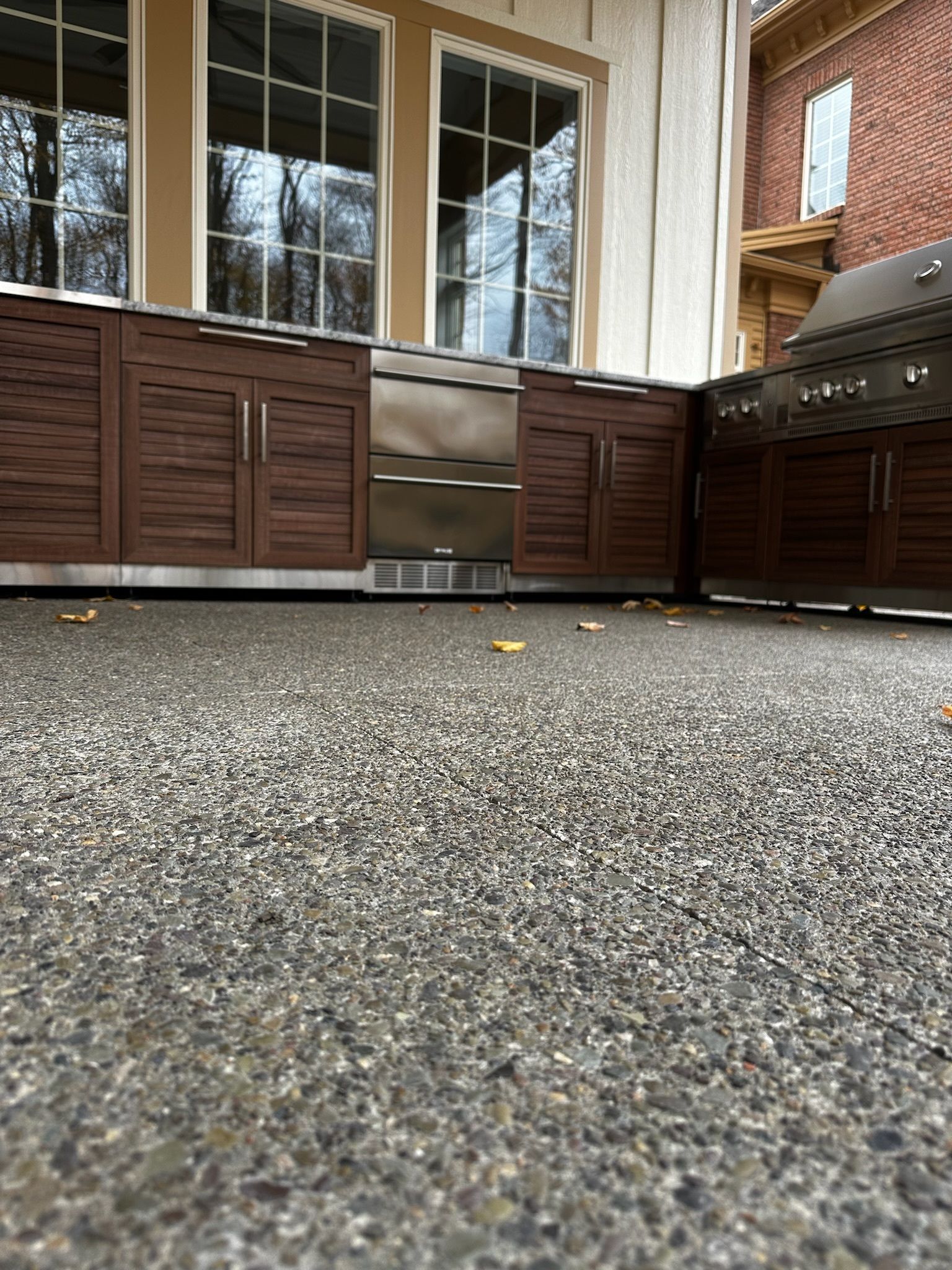 A kitchen with a grill , refrigerator , cabinets and a concrete floor.