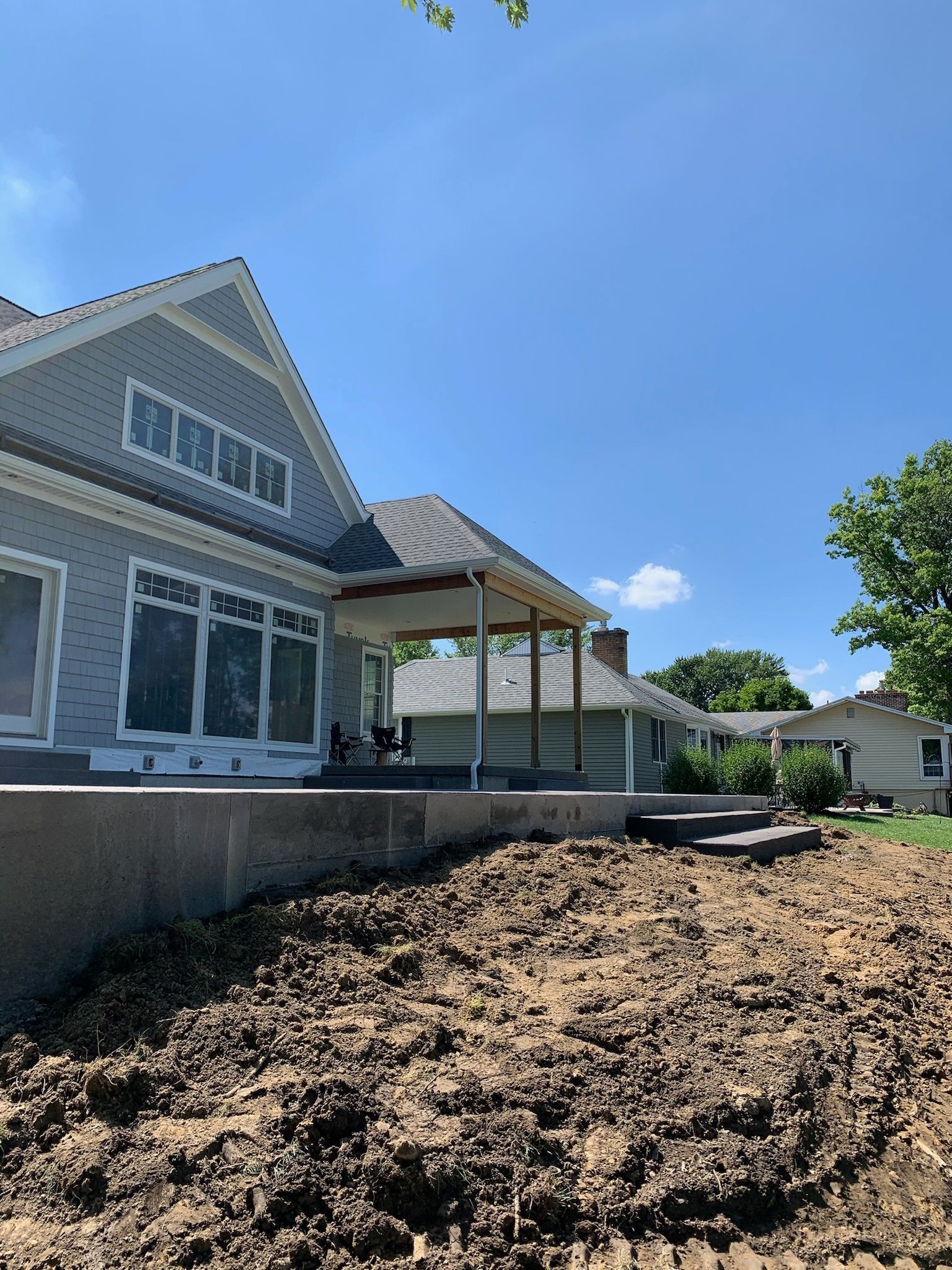 A house with a porch and a lot of dirt in front of it.