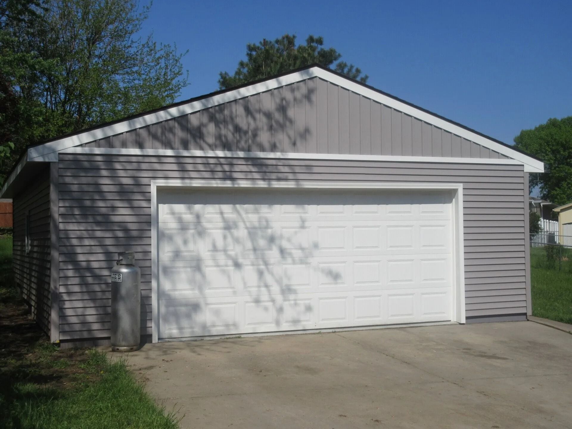 Gray garage with white garage door and concrete driveway.