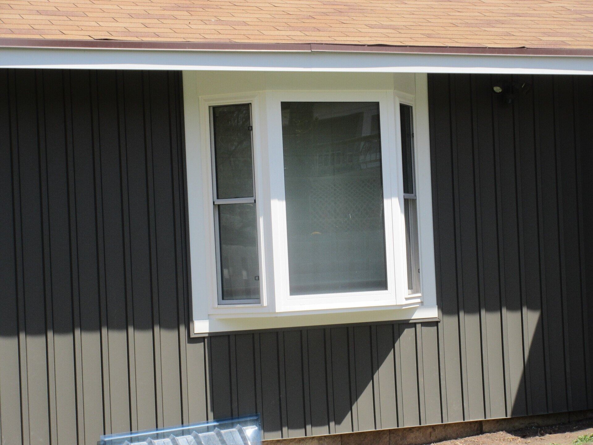 Bay window with white trim on a dark gray house.
