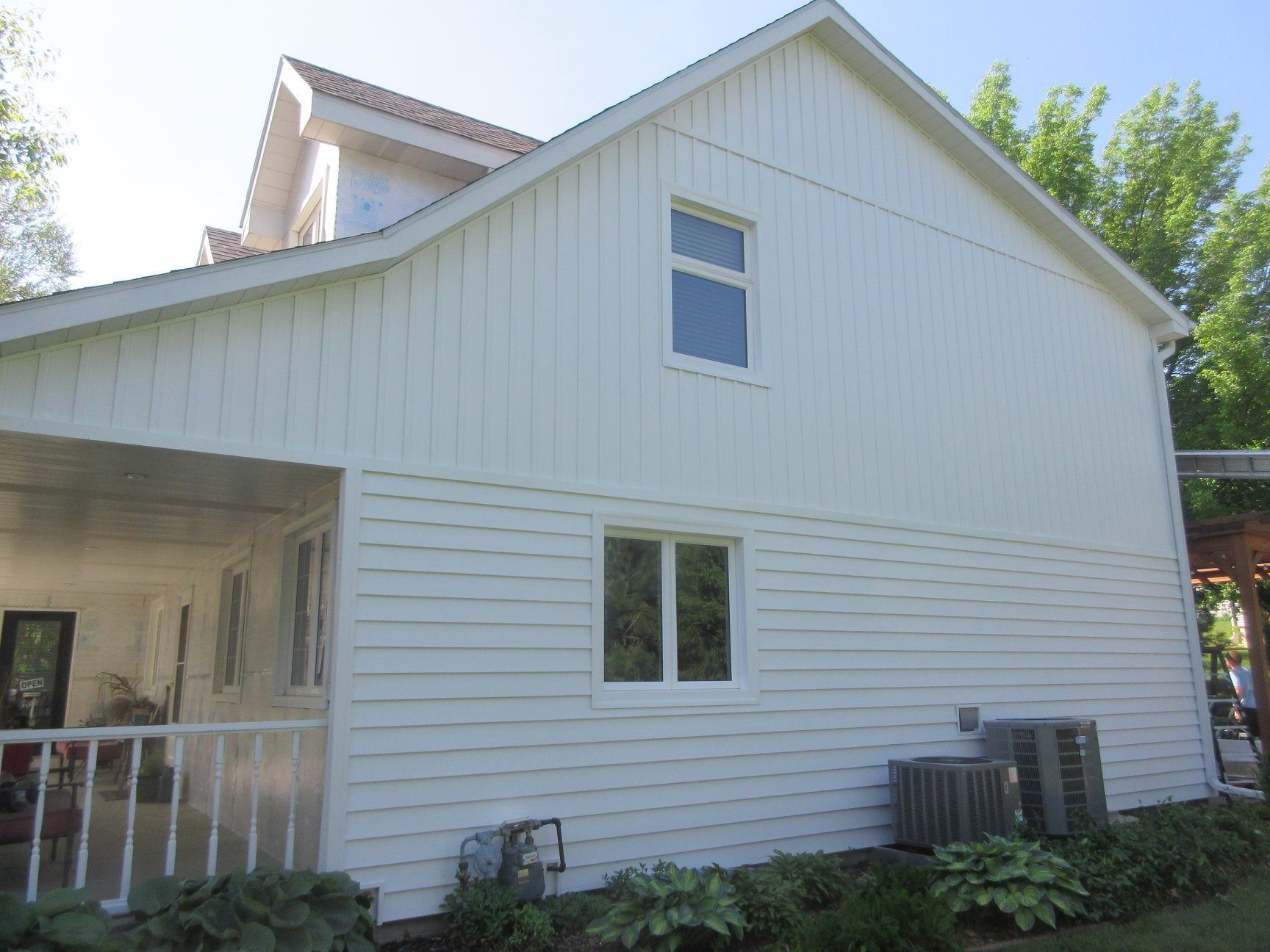 White house with vertical and horizontal siding; porch and window detail.