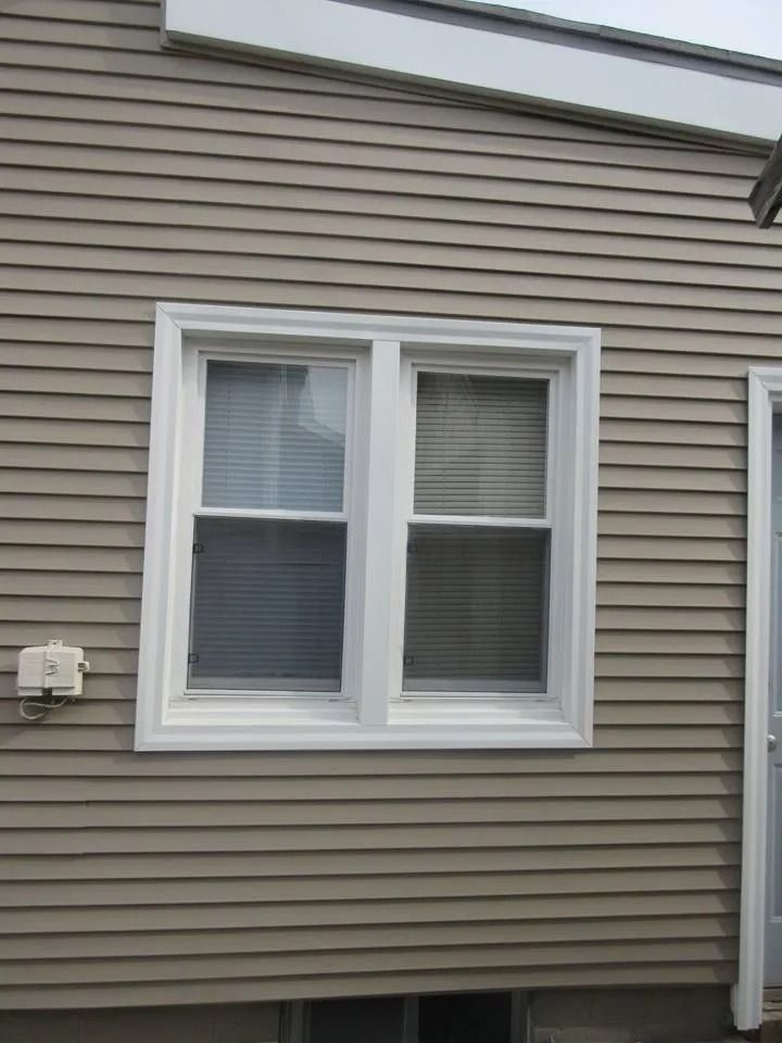 Two-pane window with white trim on a beige clapboard-sided building, closed blinds visible.
