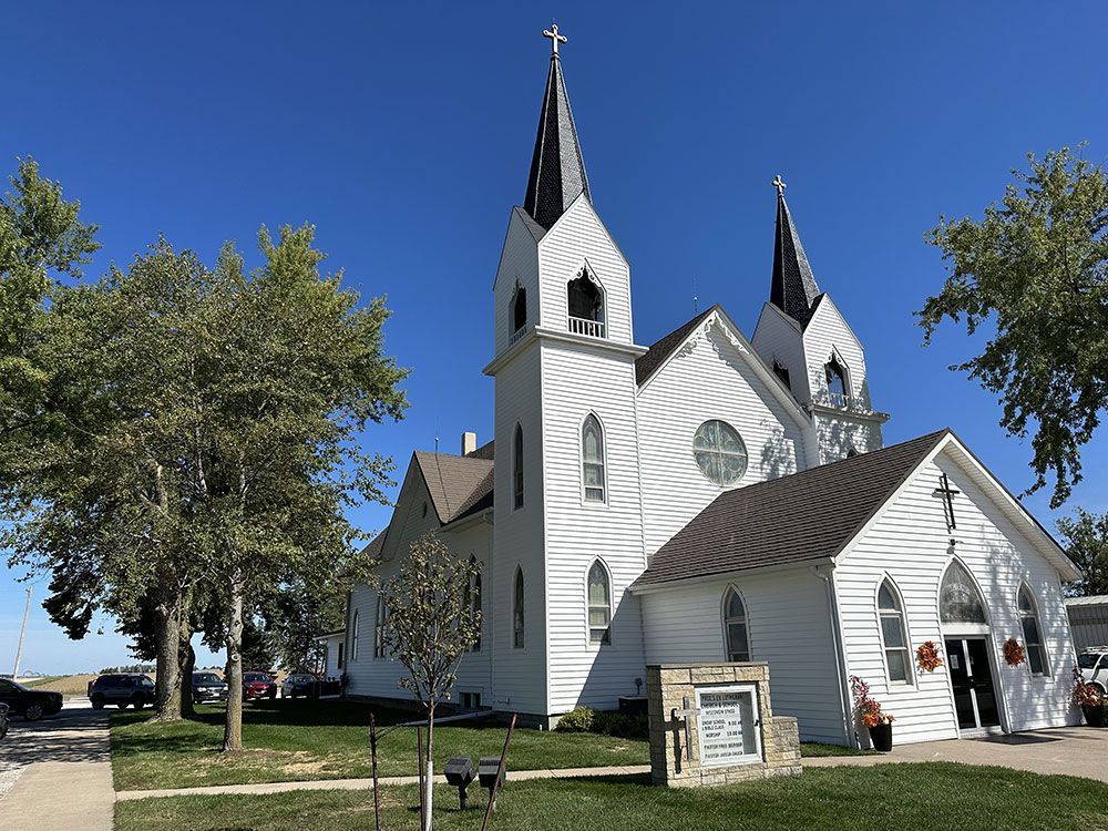 White church with two spires under a blue sky, on a sunny day.
