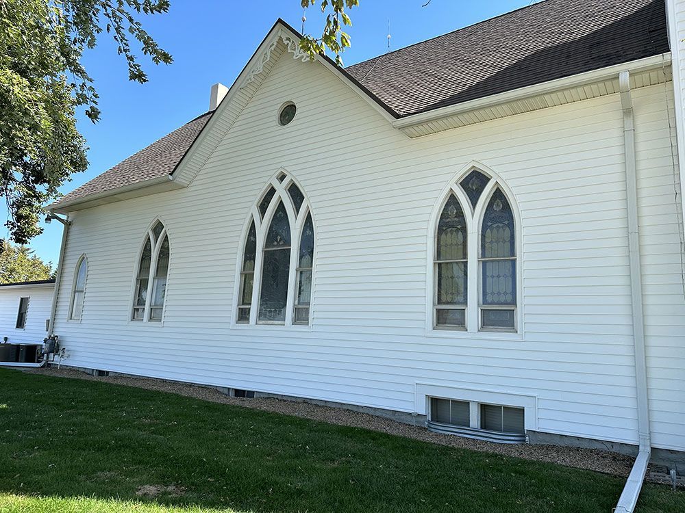 White clapboard church building with gothic arched windows and dark roof.