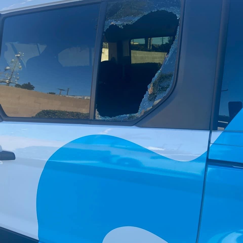 Side of a white and blue vehicle with a shattered window. Interior of the vehicle is visible.