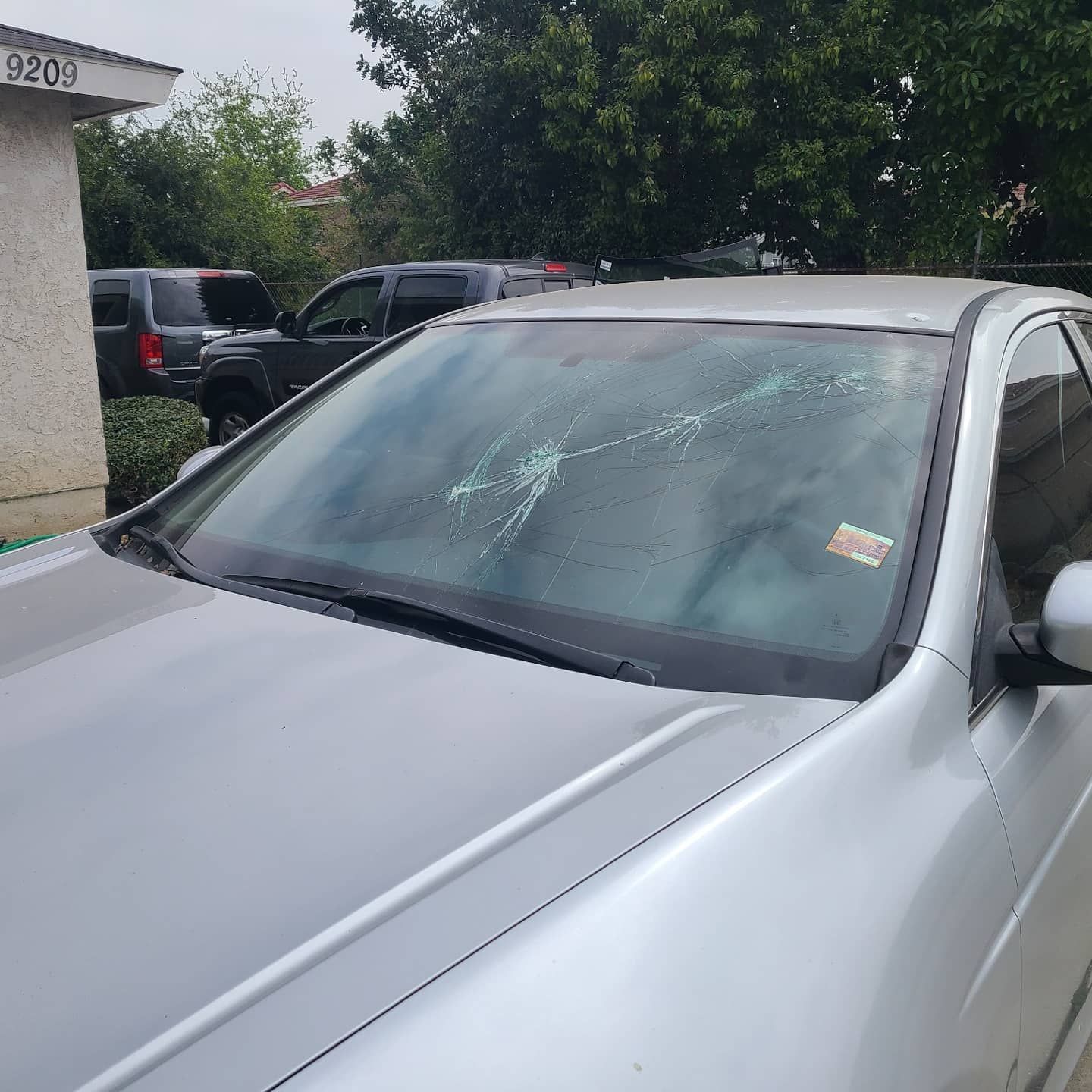Silver car with shattered windshield, parked outside.