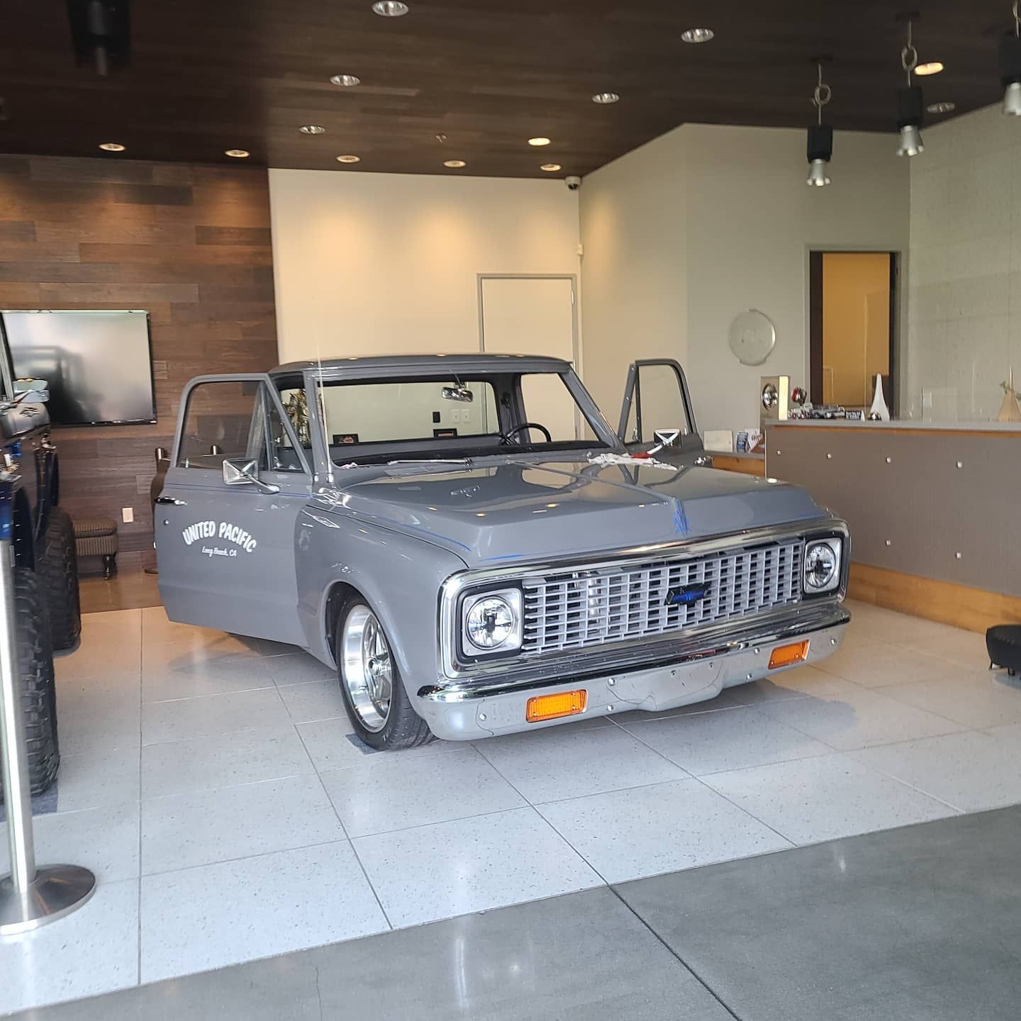 Gray classic Chevrolet truck with open doors displayed indoors.