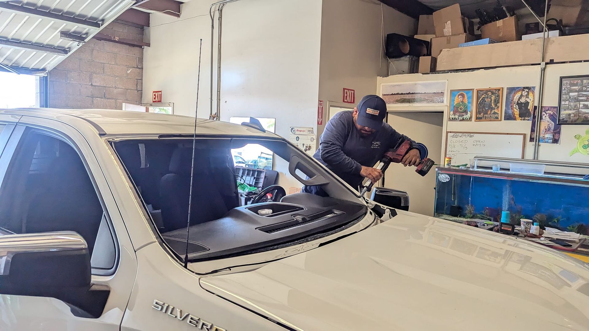 A mechanic working on a white truck windshield in a garage.