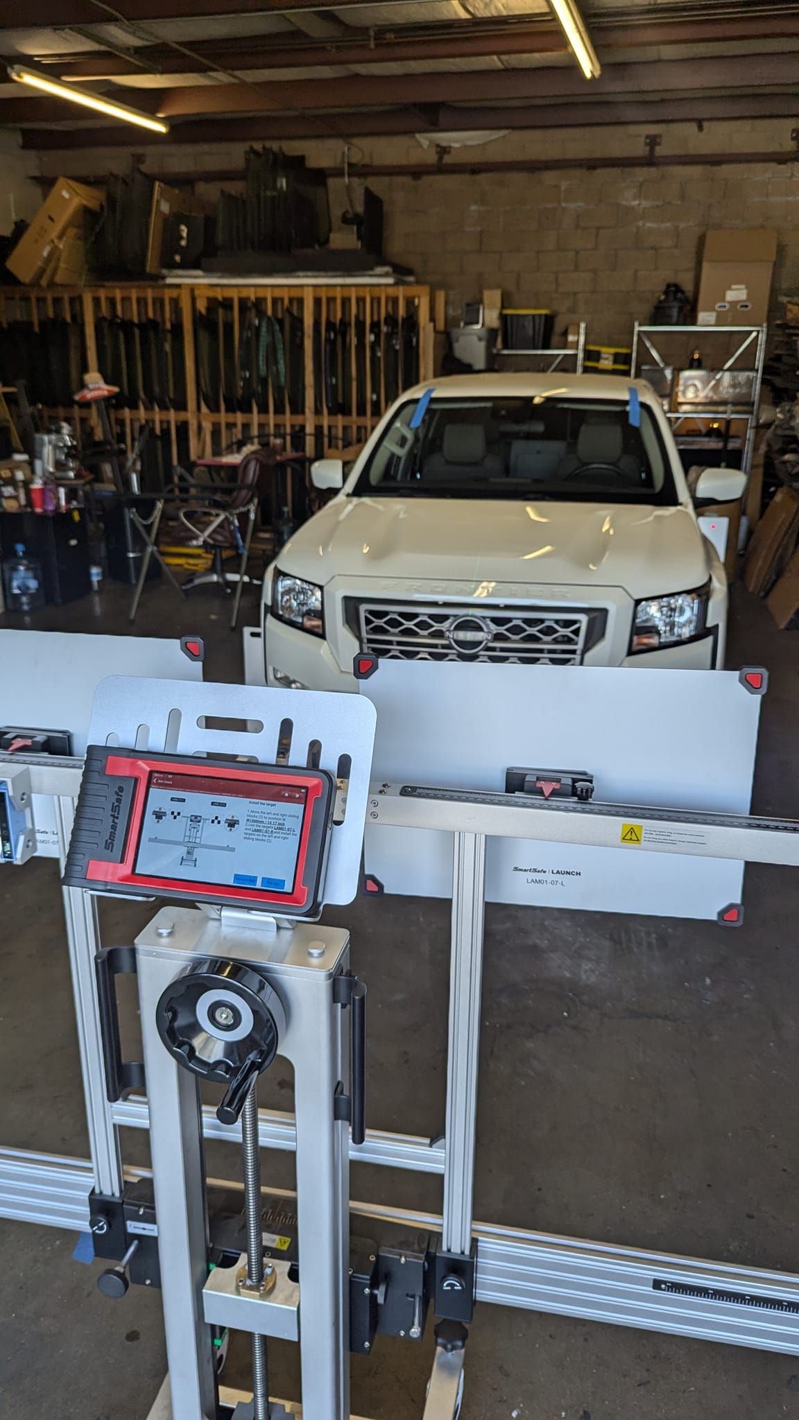 White SUV aligned by a machine in a garage. A digital device displays data.