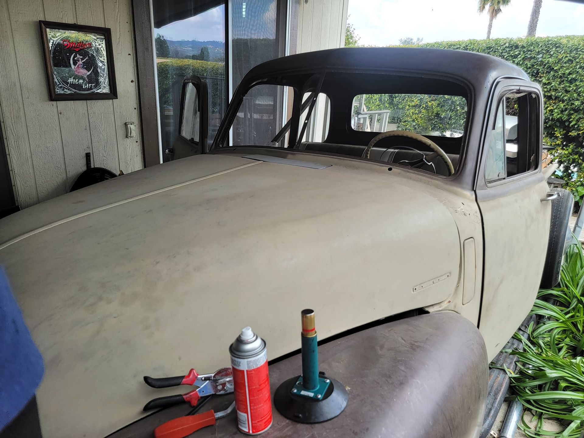 Beige classic pickup truck with tools on the hood.