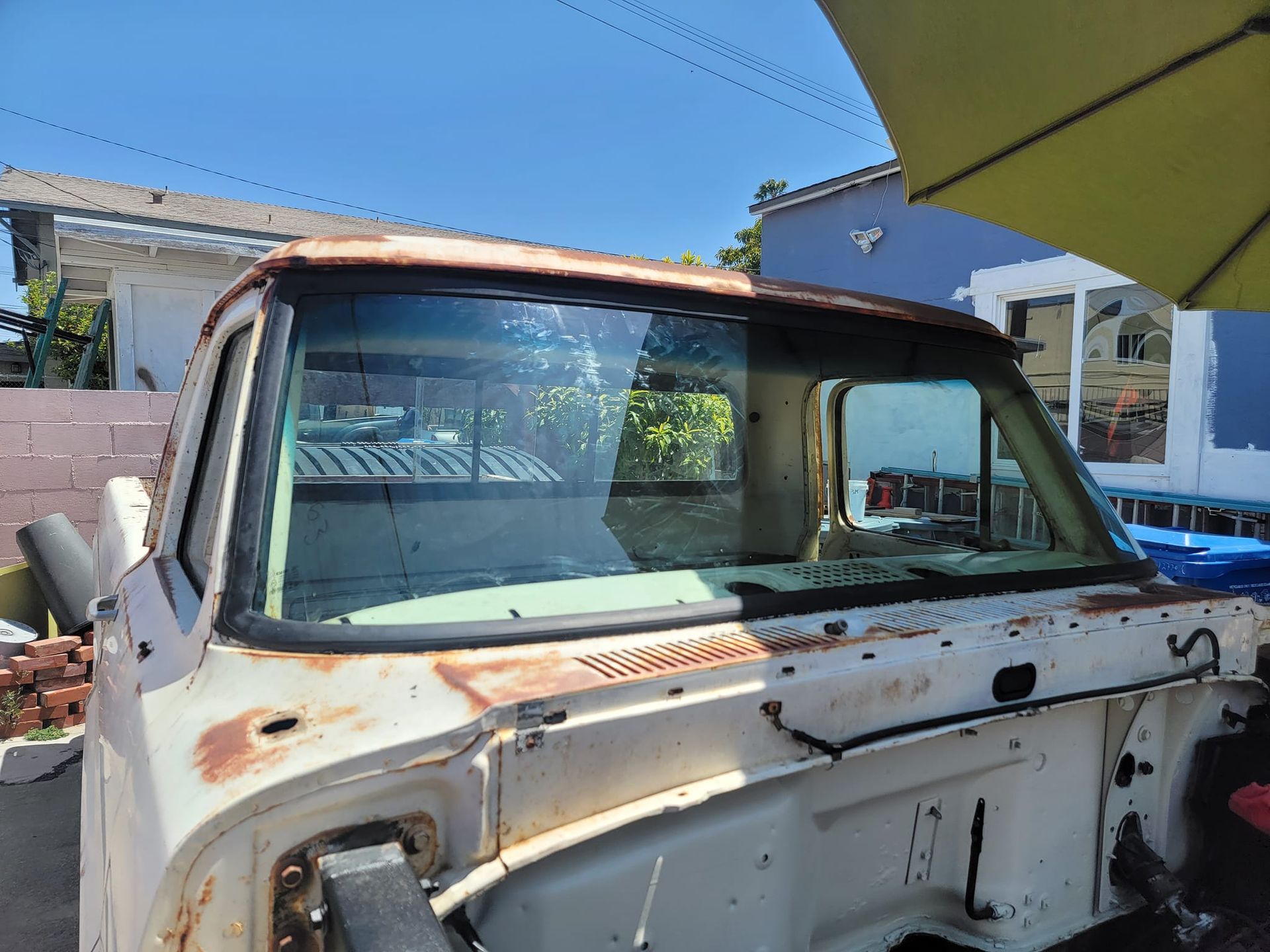 Rusty white pickup truck cab with windshield and roof.
