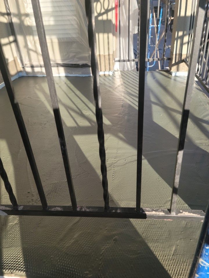 A close up of a metal railing and a concrete balcony