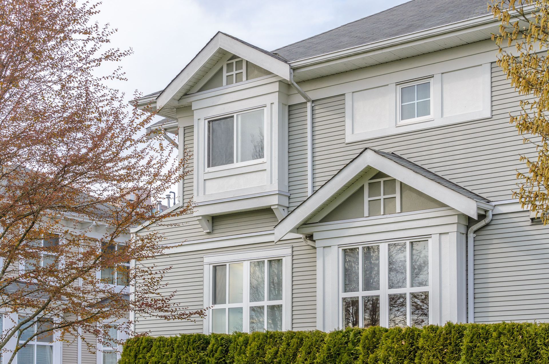 A large white house with a lot of windows and a hedge in front of it